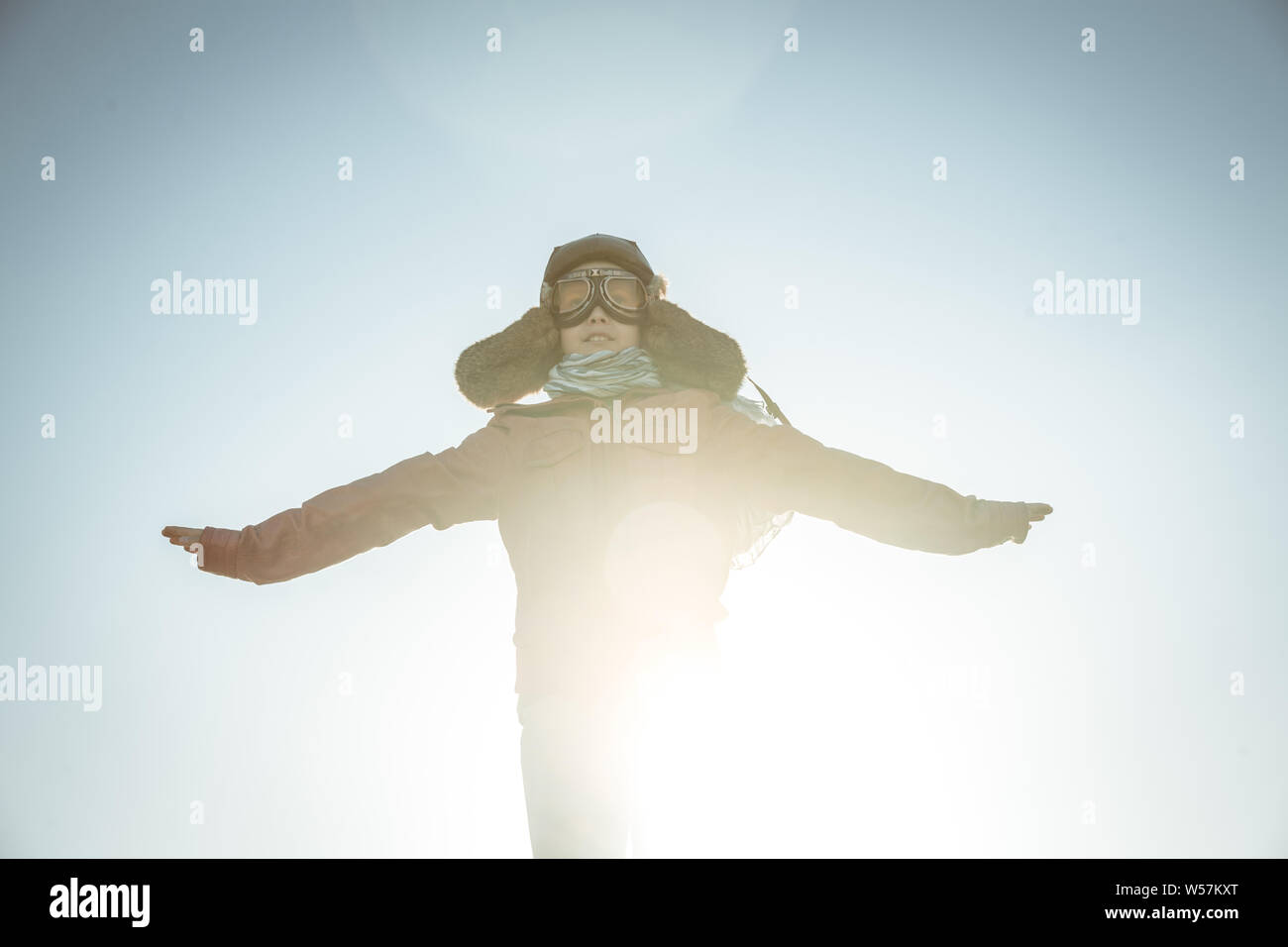 Bel ragazzo gioca felicemente gara con aereo gioiosamente fingendo di decollare dissimulata come un vintage pilota di aviazione hat, occhiali maschera giacca in pelle un Foto Stock