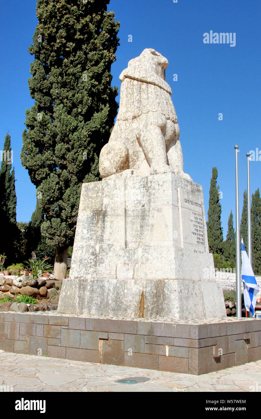 Una statua in pietra bianca di un leone che ruggisce al cielo si trova in cima a una tomba comune come memoriale per otto persone nel cimitero di Kfar Giladi. Foto Stock
