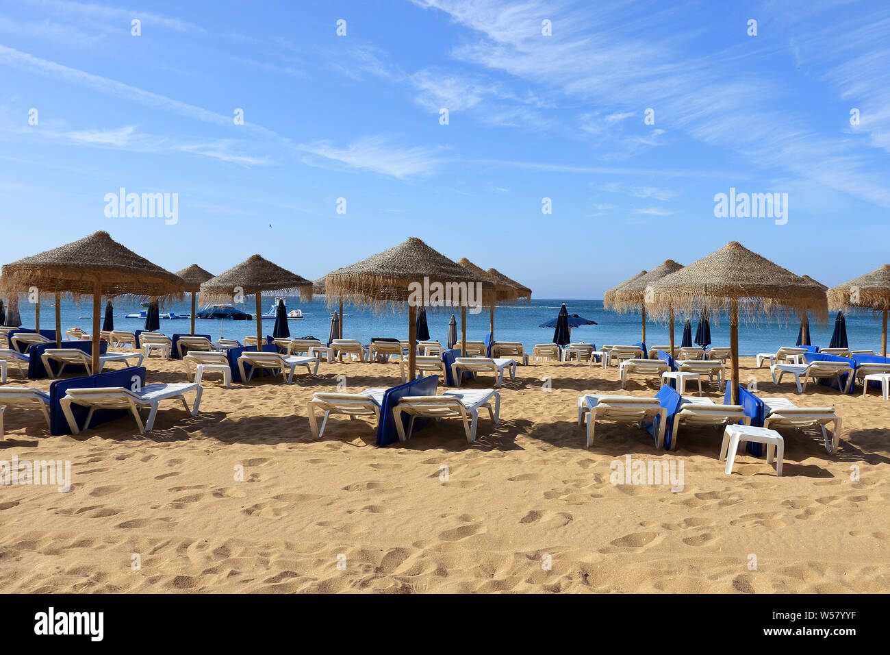La paglia di ombrelloni e sedie a sdraio sulla spiaggia di Albufeira Foto Stock