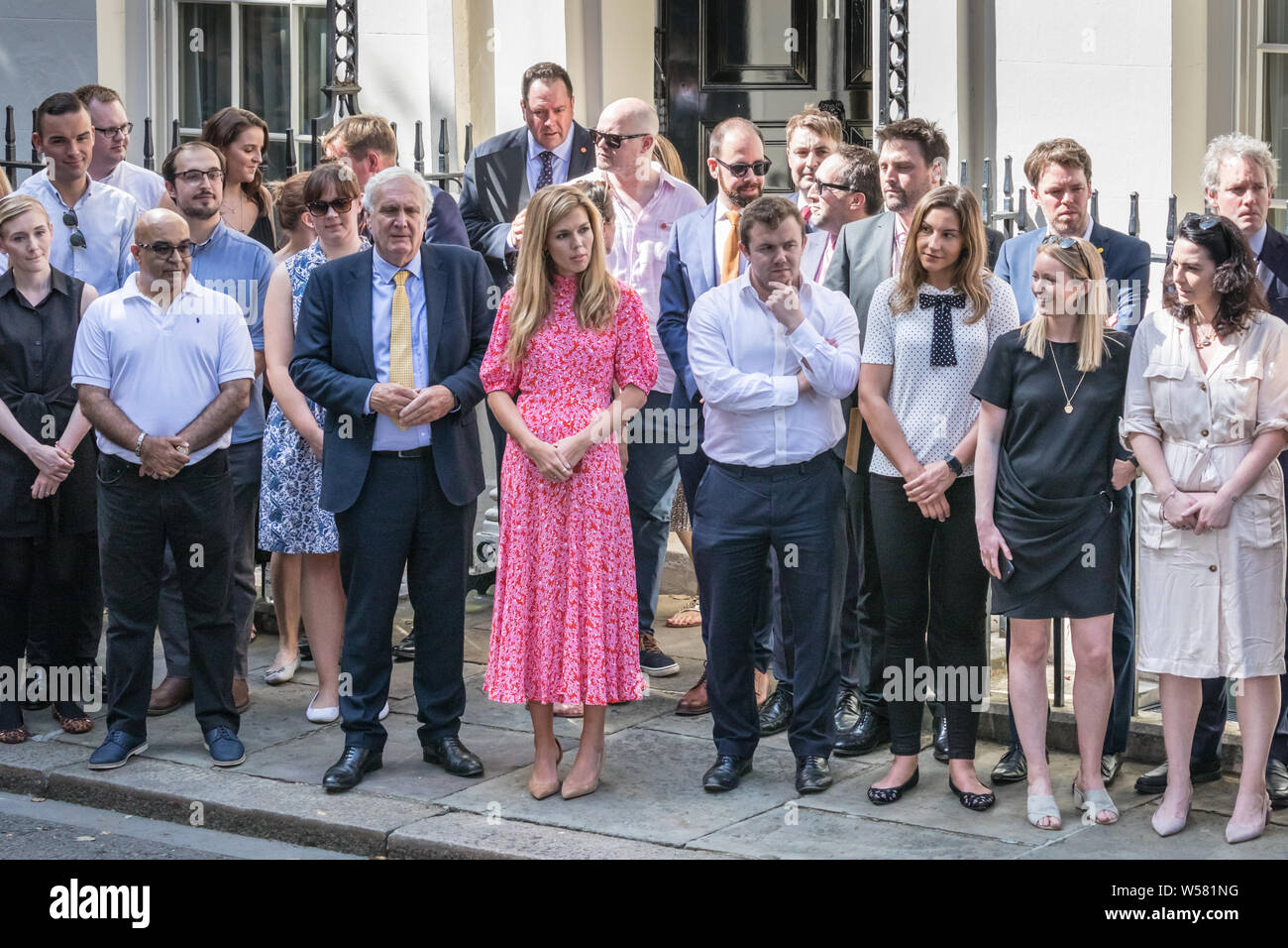 Boris Johnson la ragazza di Carrie Symonds, in abito rosa, attende con Sir Edward Lister esterno 10 di Downing Street per l arrivo del nuovo Primo Mini Foto Stock