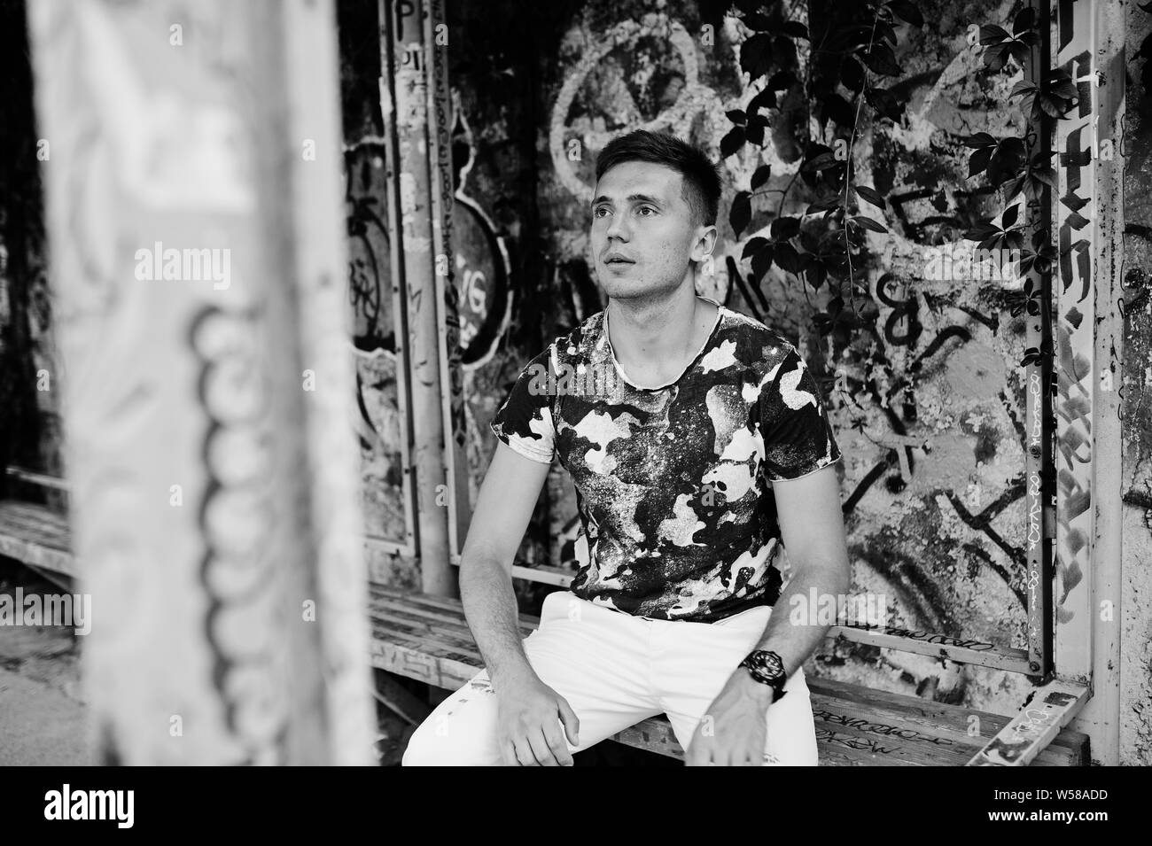 Ritratto di uno stile di vita di uomo bello in posa sulla strada di città con muro di graffiti. Foto Stock