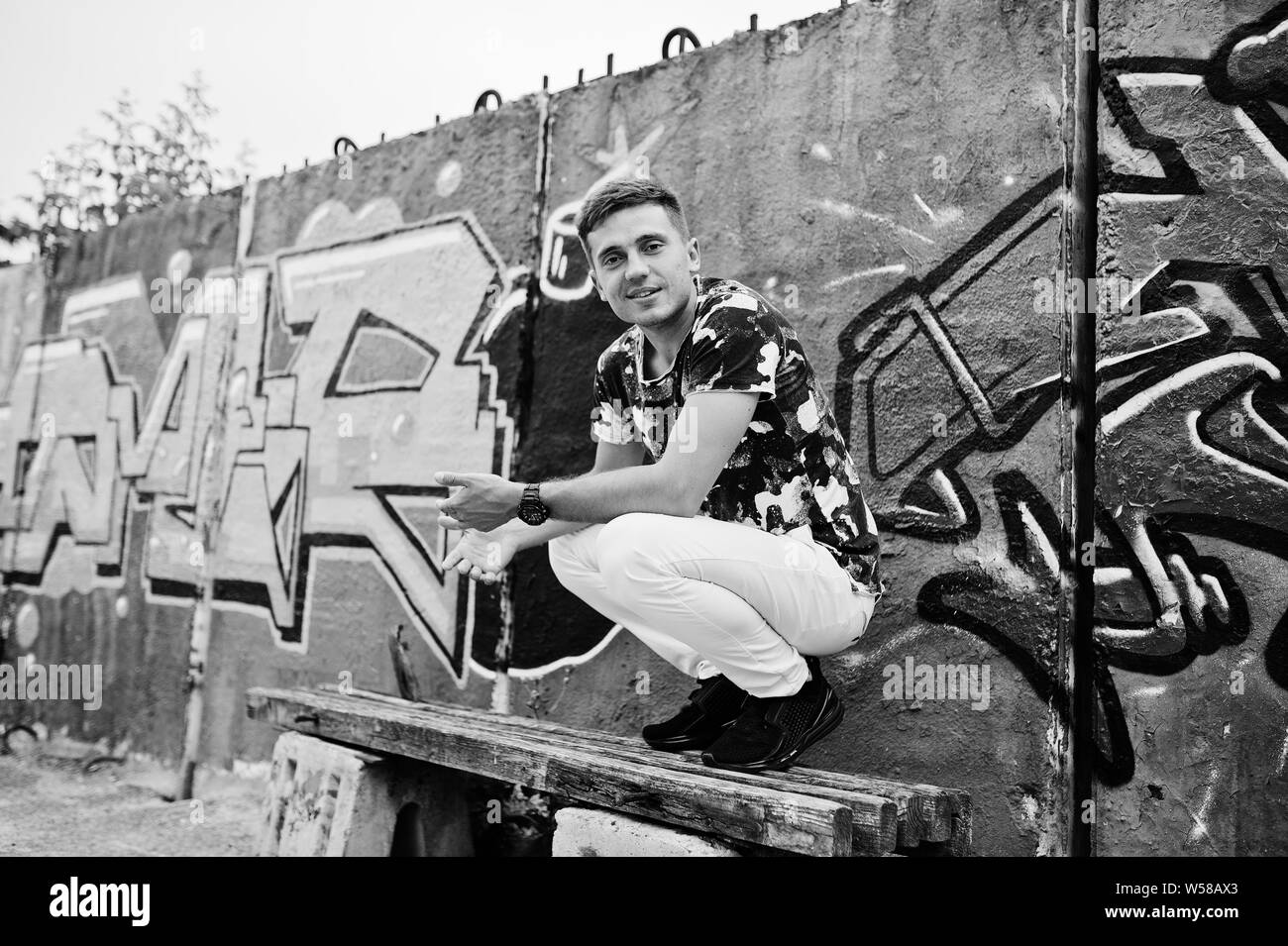 Ritratto di uno stile di vita di uomo bello in posa sulla strada di città con muro di graffiti. Foto Stock