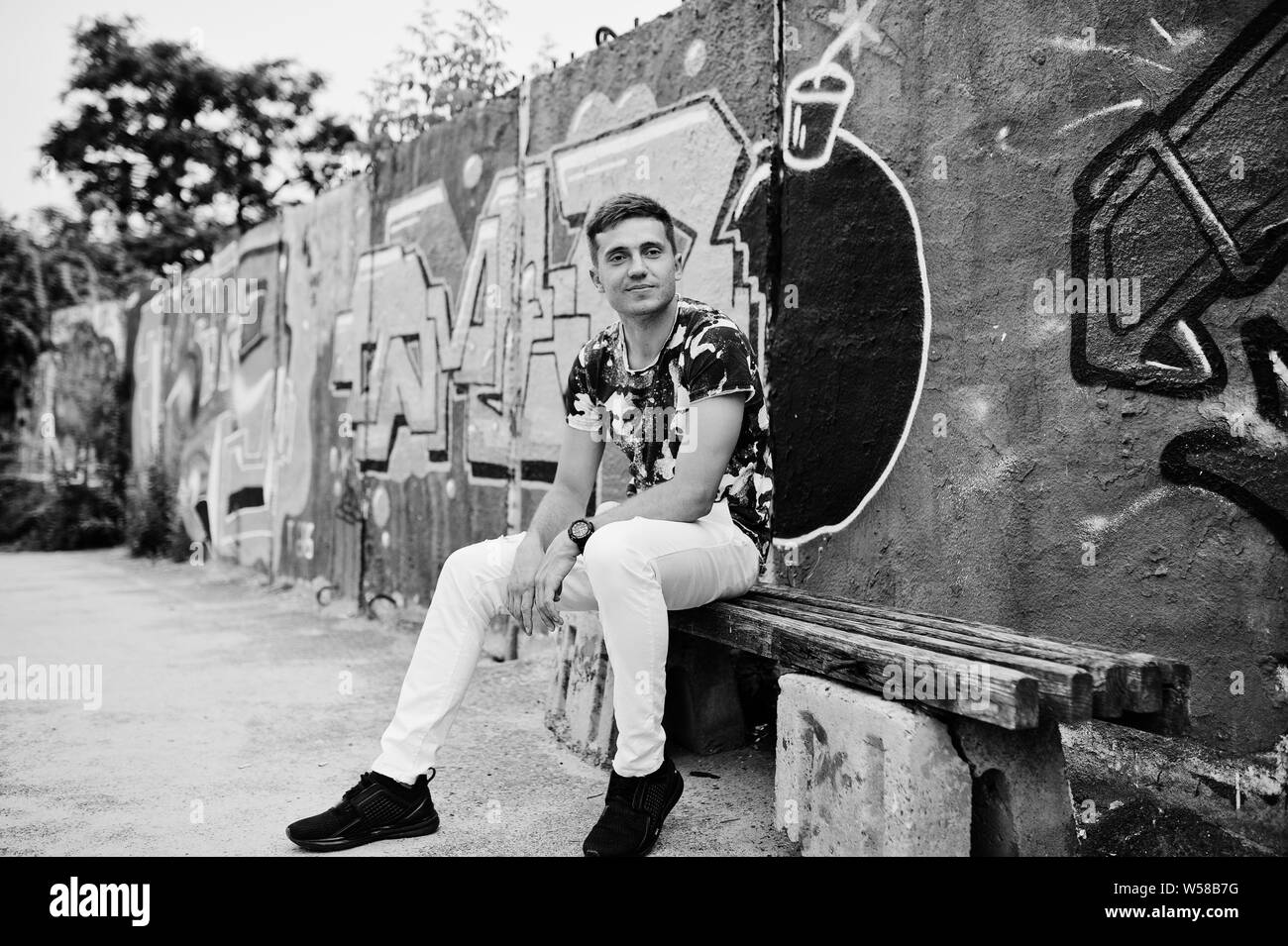 Ritratto di uno stile di vita di uomo bello in posa sulla strada di città con muro di graffiti. Foto Stock