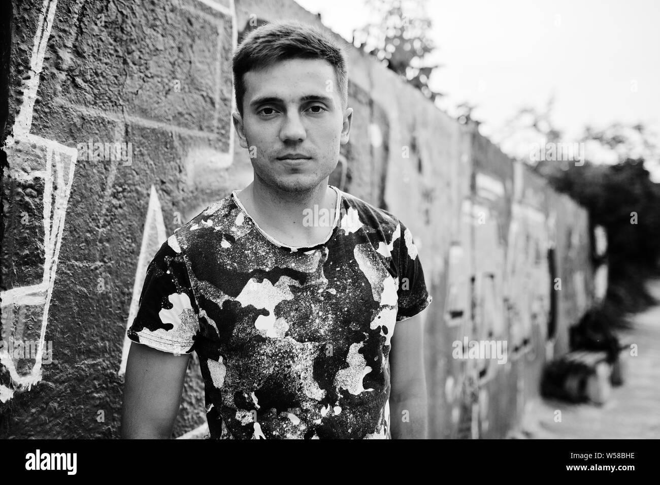 Ritratto di uno stile di vita di uomo bello in posa sulla strada di città con muro di graffiti. Foto Stock
