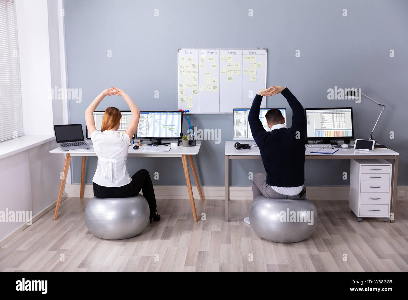 Vista posteriore del businessman seduti sulla sfera di Fitness con il braccio sollevato al lavoro Foto Stock