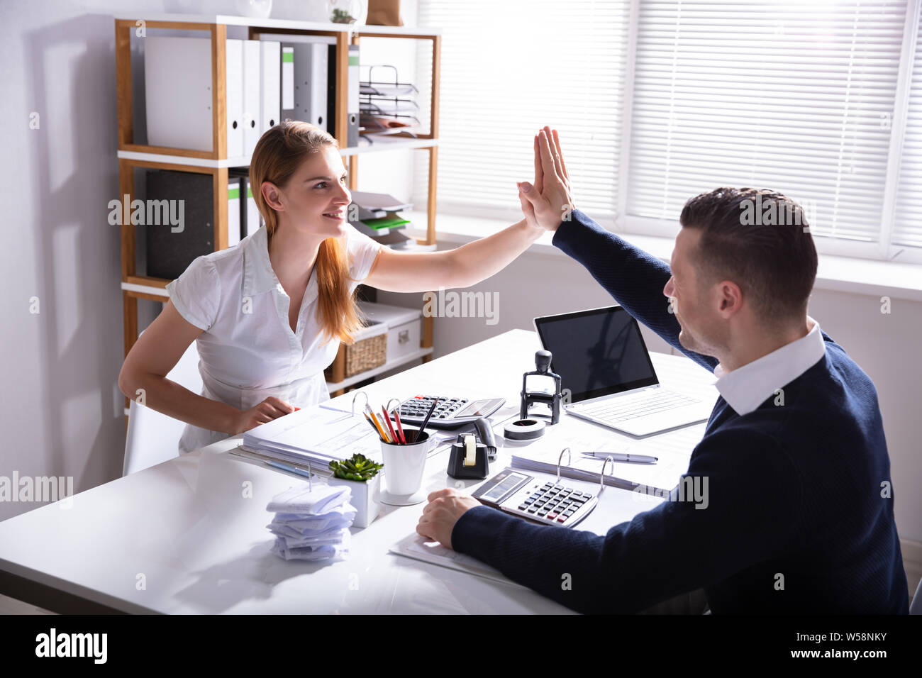 Happy Businessman dando alta cinque al suo collega in ufficio Foto Stock