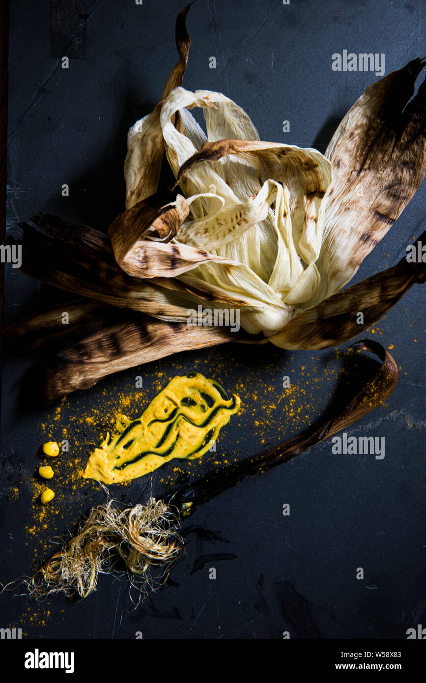 Carbonizzati Corn buccia giallo con dressing e spezie su piastrelle nere Foto Stock