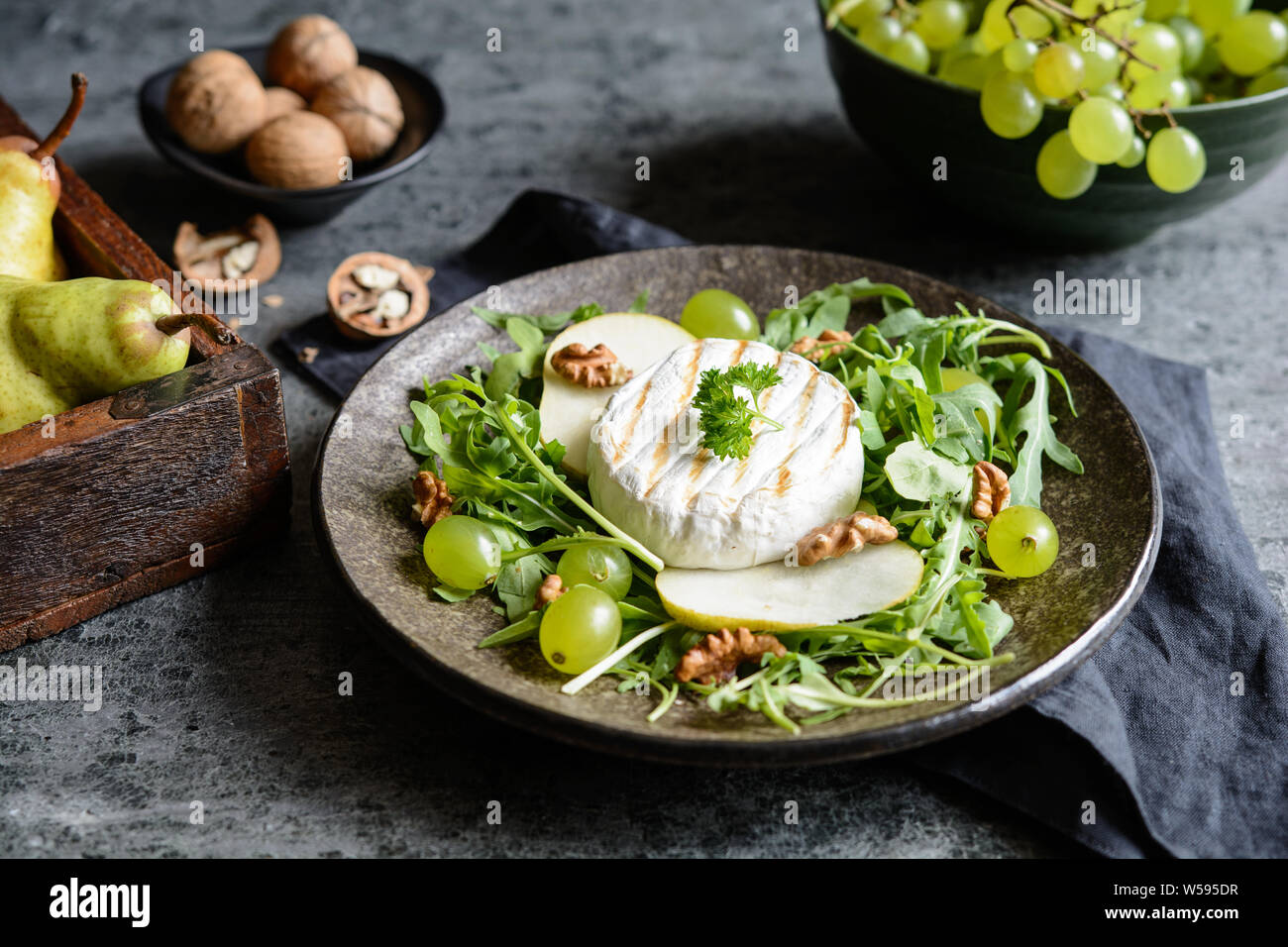 Grigliata di formaggio Camembert, servita con rucola fresca, verde uva e pere e noci Foto Stock