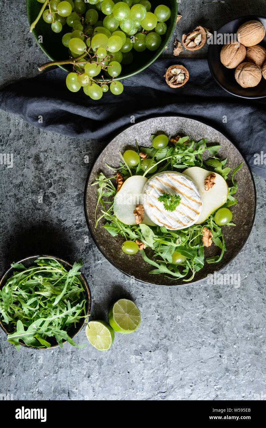 Grigliata di formaggio Camembert, servita con rucola fresca, verde uva e pere e noci Foto Stock