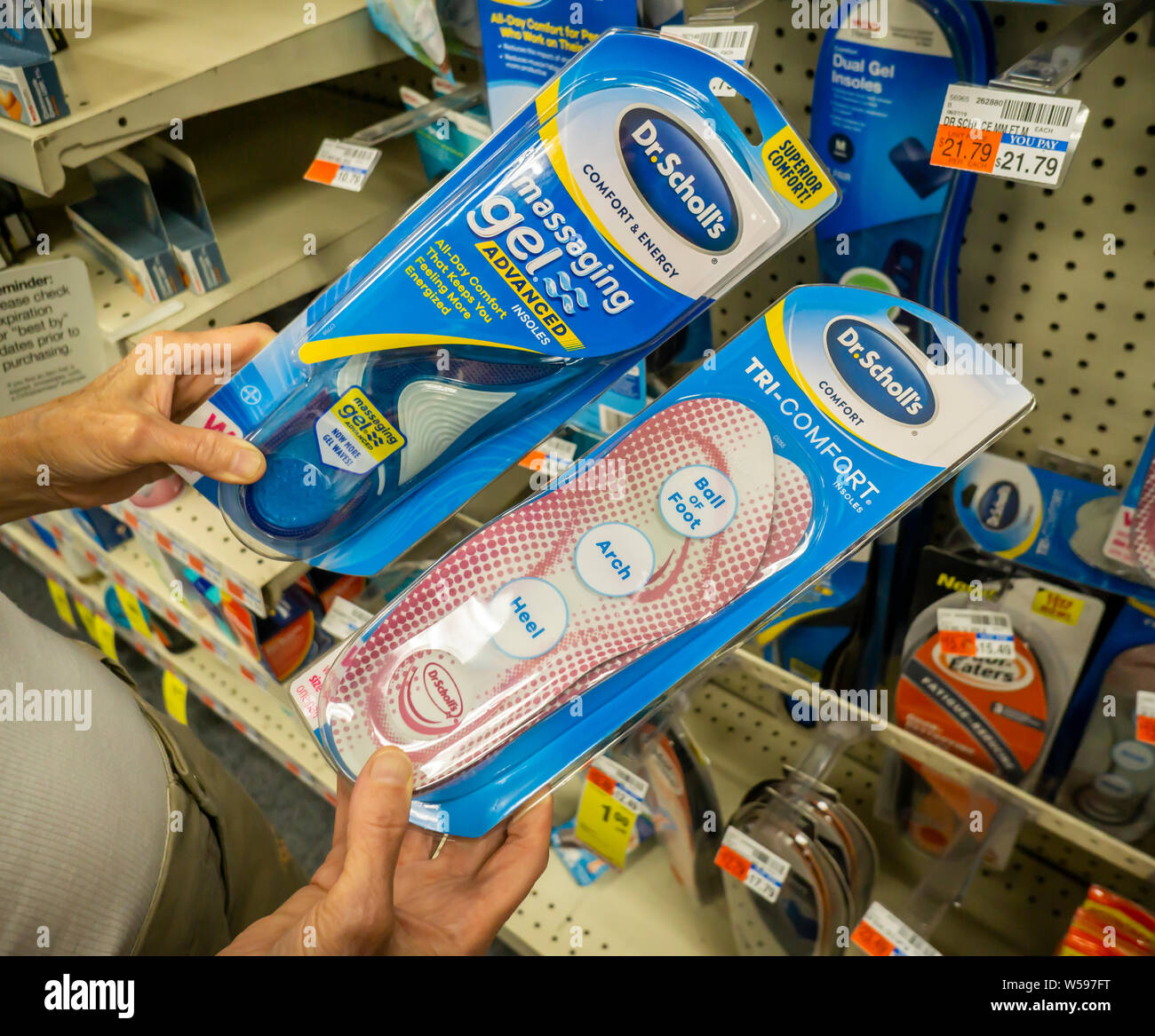 Un consumatore esigente Confronta pacchetti di Dr. Scholl il sostegno ortotico in una farmacia a New York lunedì 22 luglio, 2019. Bayer, il proprietario del Dr. Scholl, ha venduto la marca di legno giallo Partners, una società privata di investimento in un $585 milioni di trattativa. Bayer ha acquistato il marchio da Merck in 2014. (© Richard B. Levine) Foto Stock