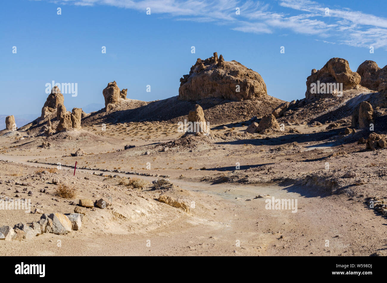 Sentiero da formazioni rocciose nel desolato deserto arido. I cieli blu, pinnacoli gettando ombre. Foto Stock