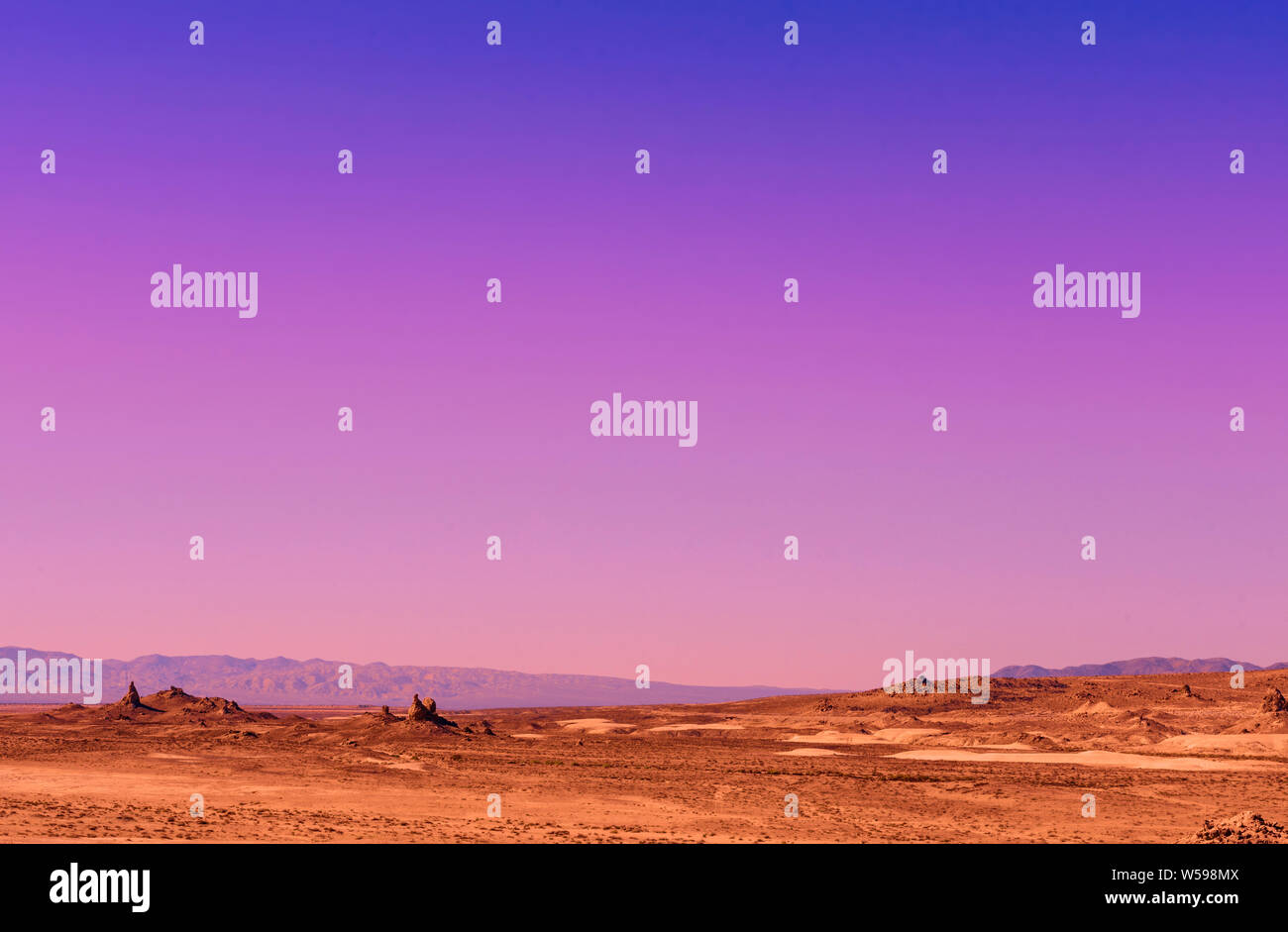 Tramonto sul deserto arido paesaggio. Sky cambia da blu, viola, rosa pallido arancioni su vallata desertica. Foto Stock