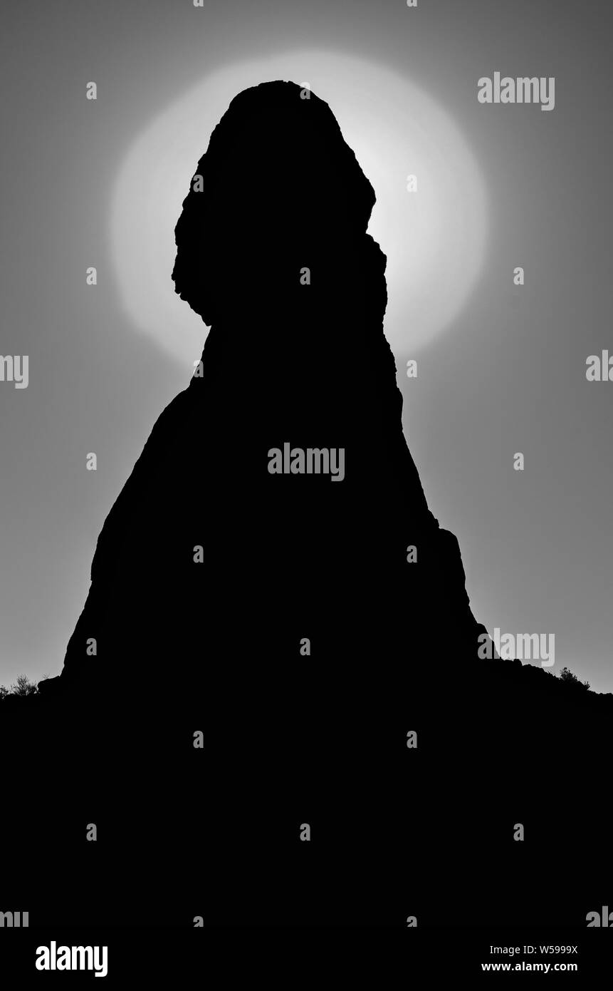 Retroilluminato con formazione di roccia con luce intensa direttamente dietro la parte superiore del pinnacle. In bianco e nero. Foto Stock