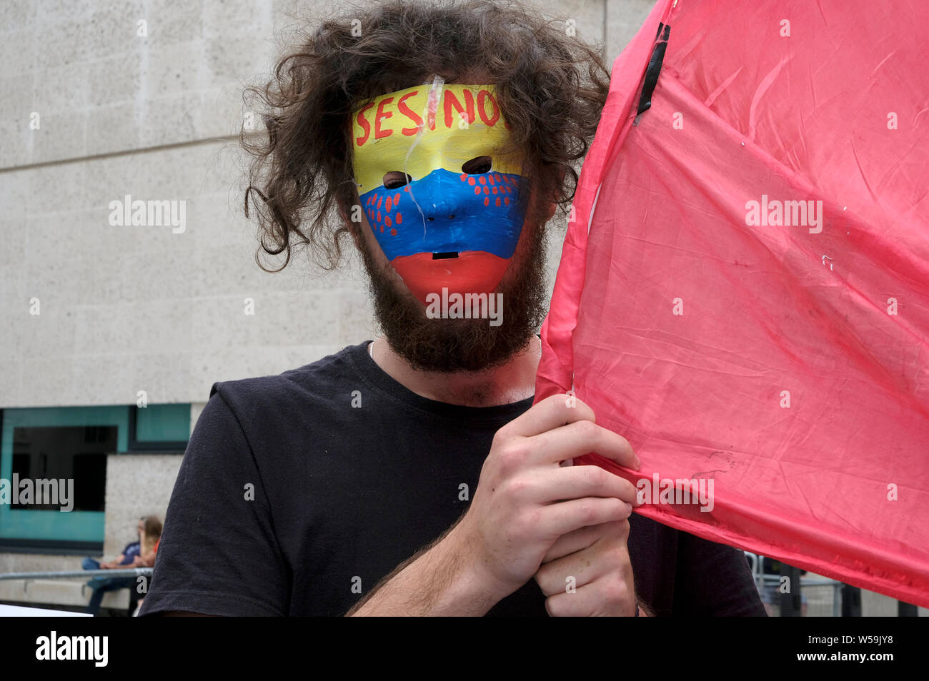 Un manifestante è visto indossare una maschera con il colombiano bandiera colori scrive sulla sommità Asesinos (assassini) durante la protesta a Londra. I colombiani si sono riuniti al di fuori della BBC a Londra per protestare contro le continue uccisioni di leader di comunità, attivisti sociali, e le FARC ex guerriglieri, in Colombia. Essi hanno marciato attraverso il centro di Londra a Piazza del Parlamento tenendo un lungo banner con i nomi dei più di 700 dirigenti sociali che sono stati uccisi in Colombia Negli ultimi tre anni. I manifestanti sostengono la pace e i diritti umani in Colombia e la domanda al governo di prendere azione diretta a proteggere c Foto Stock
