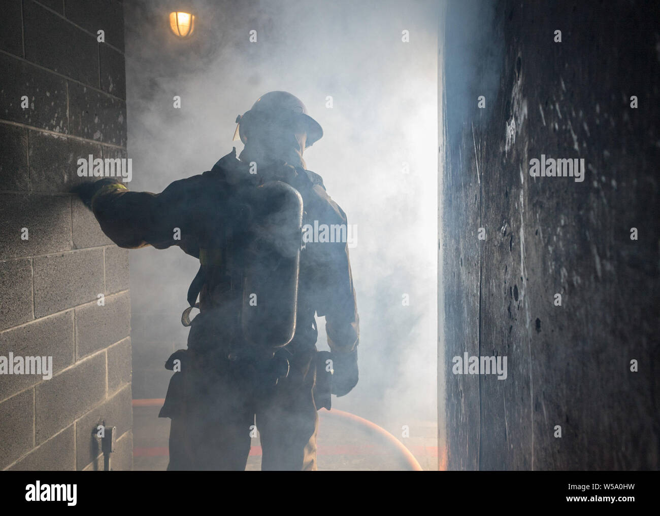 Un USS Carl Vinson Sailor entra in una piena di fumo nello spazio in una lotta antincendio training facility a Bremerton, Washington, 24 luglio 2019. (U.S. Foto di Marina di Massa Specialista comunicazione marinaio Christina Ross/rilasciato) Foto Stock
