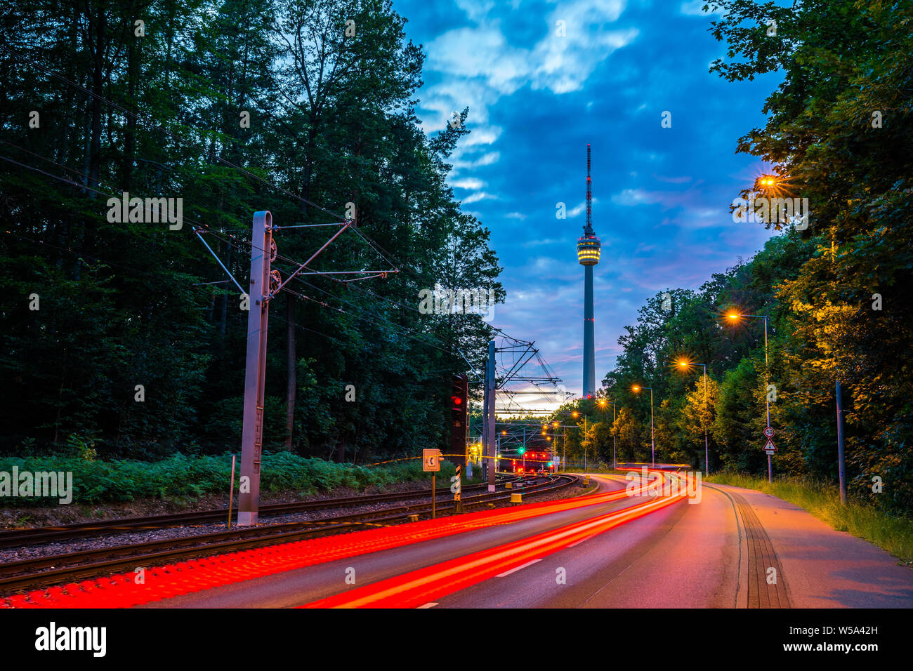 Germania, accese le luci di tracciante di automobili e il traffico sulla strada per il famoso Stoccarda Fernsehturm (torre della televisione) dopo il tramonto nel Magico crepuscolo surrou Foto Stock