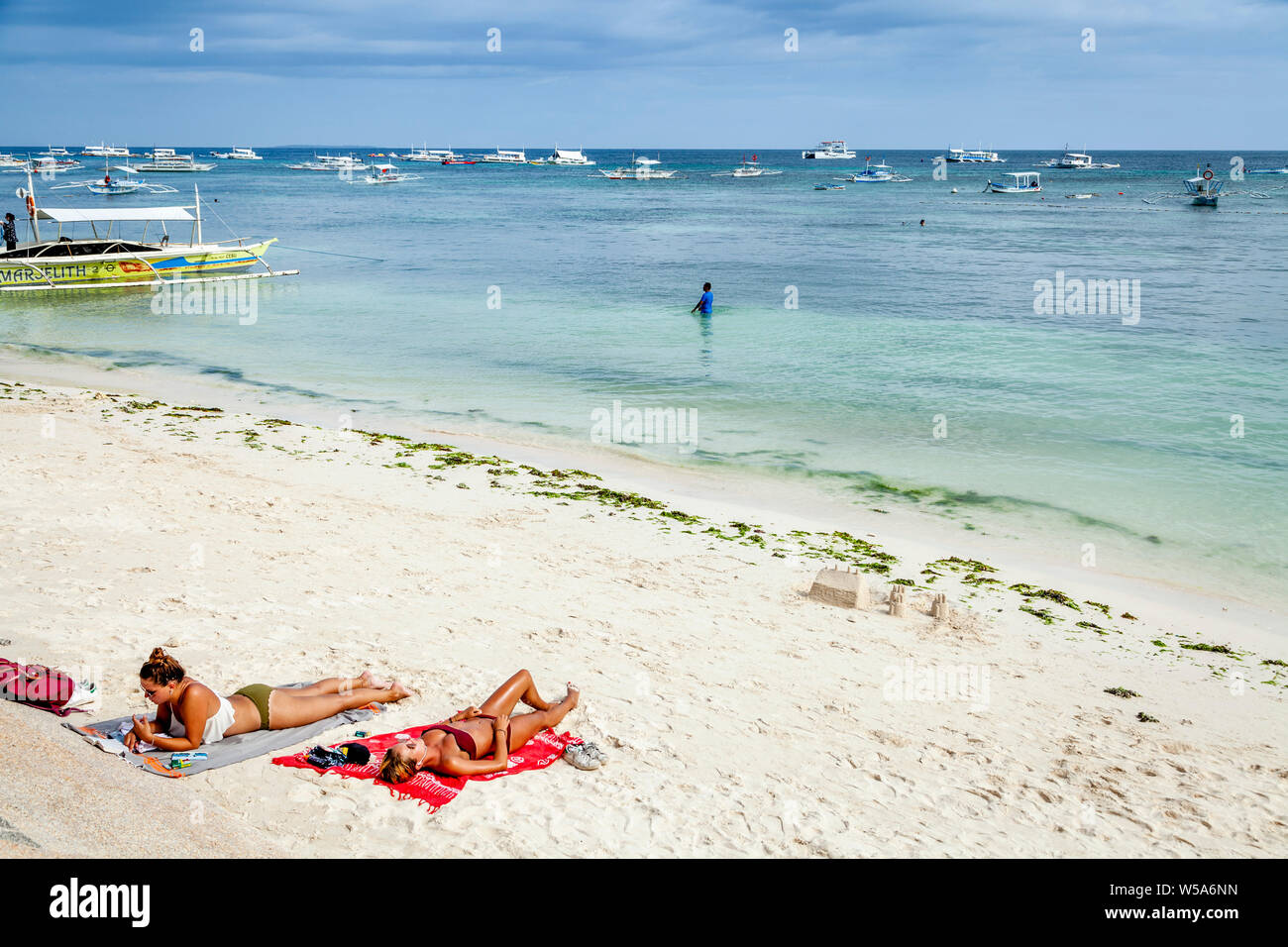 Le giovani donne a prendere il sole su Alona Beach, Bohol, Filippine Foto Stock