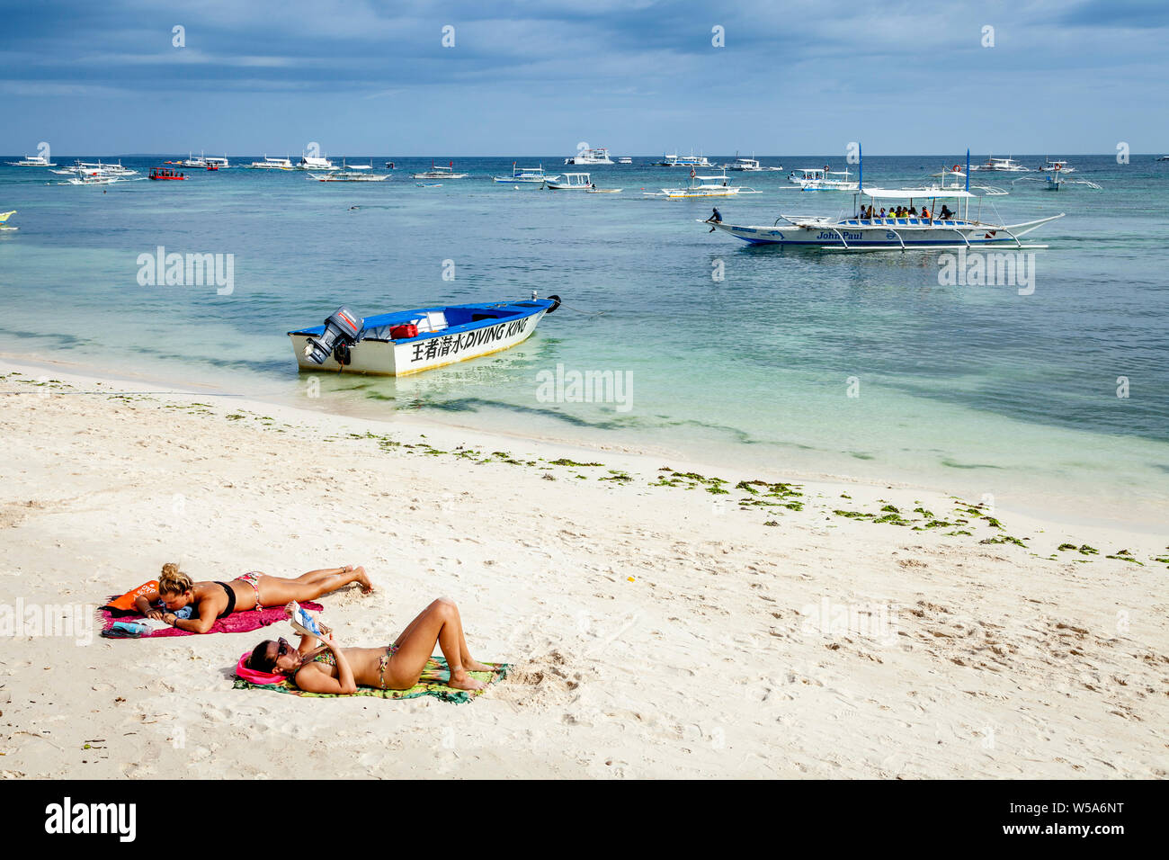 Le giovani donne a prendere il sole su Alona Beach, Bohol, Filippine Foto Stock