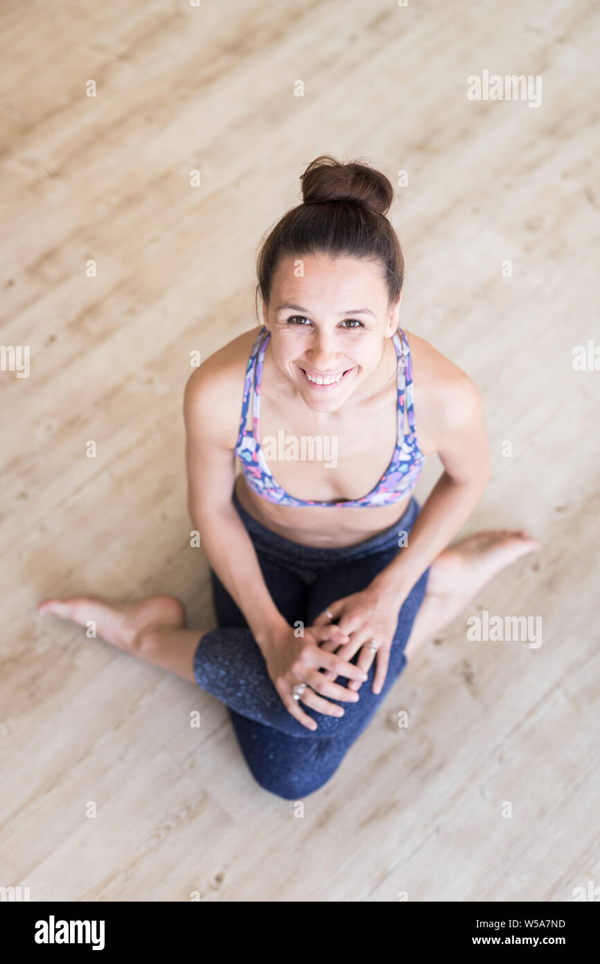 Montare sportivo ragazza attiva in sportswear seduto sul pavimento in studio di yoga. Attiva uno stile di vita urbano Foto Stock