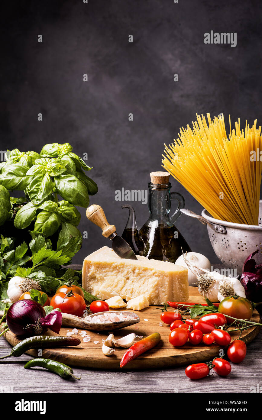 Gli ingredienti per cucinare gli spaghetti con sugo di pomodoro con basilico fresco, olio d'oliva e parmigiano Foto Stock