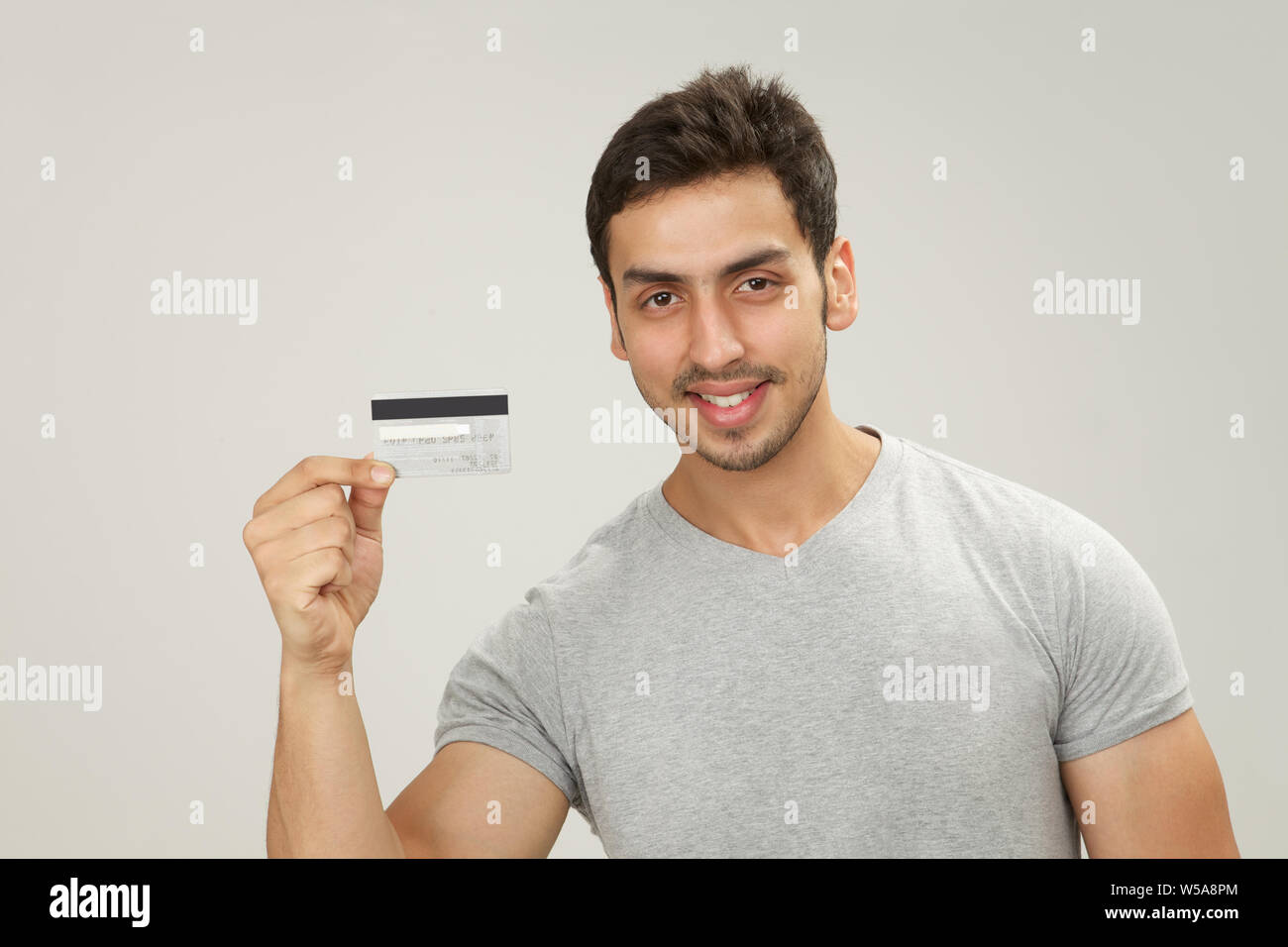 Uomo che mostra una carta di credito e sorridente Foto Stock