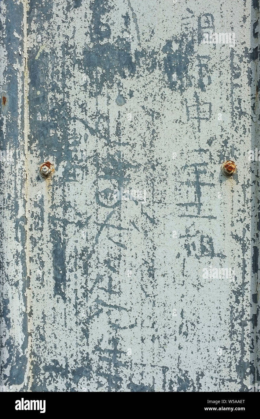 Incrinato vernice scrostata e graffitied su una recinzione metallica. Foto Stock