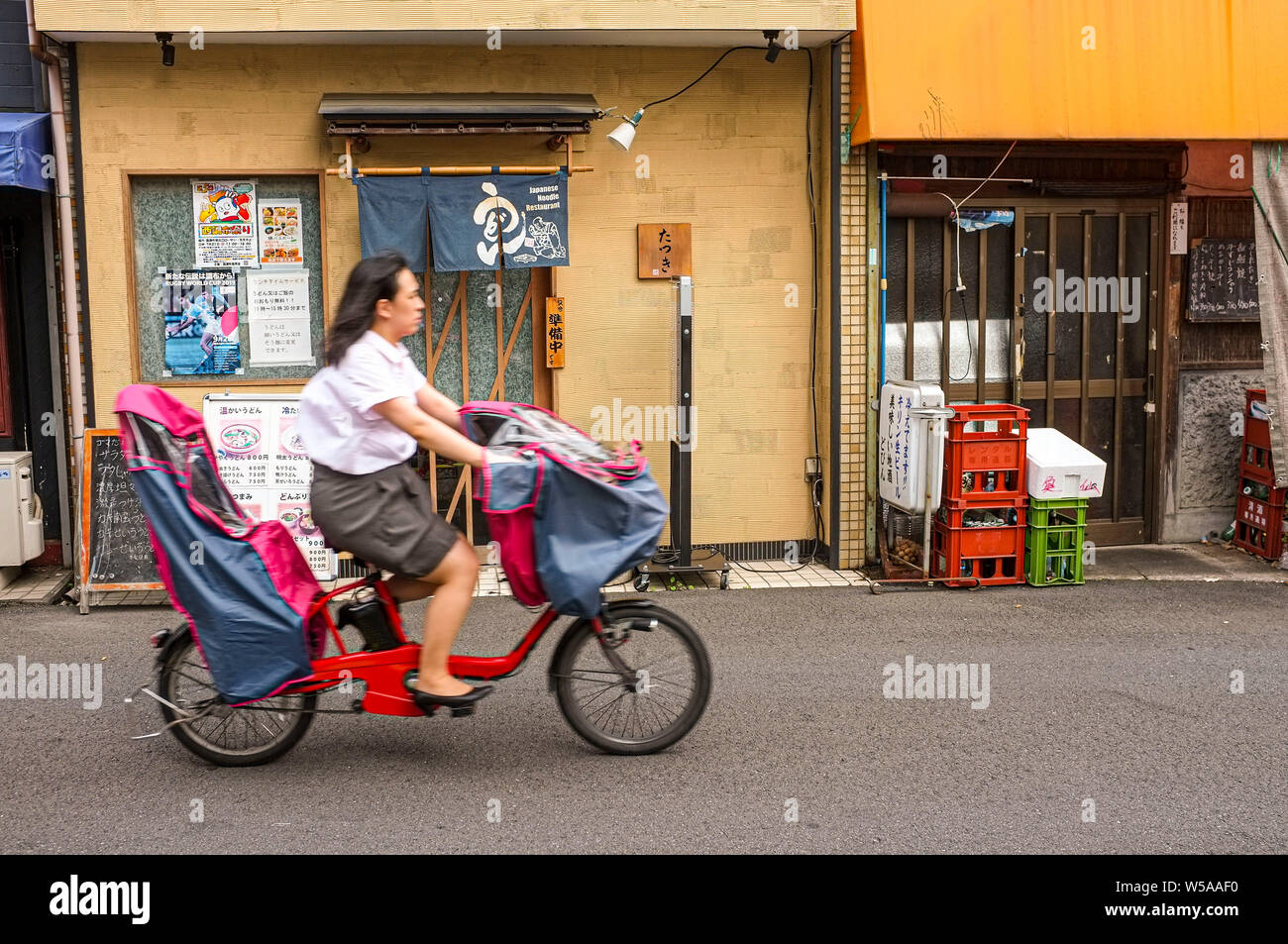 Una donna un giro in bicicletta di fronte ad un ristorante a Chofu Tokyo Giappone. Foto Stock