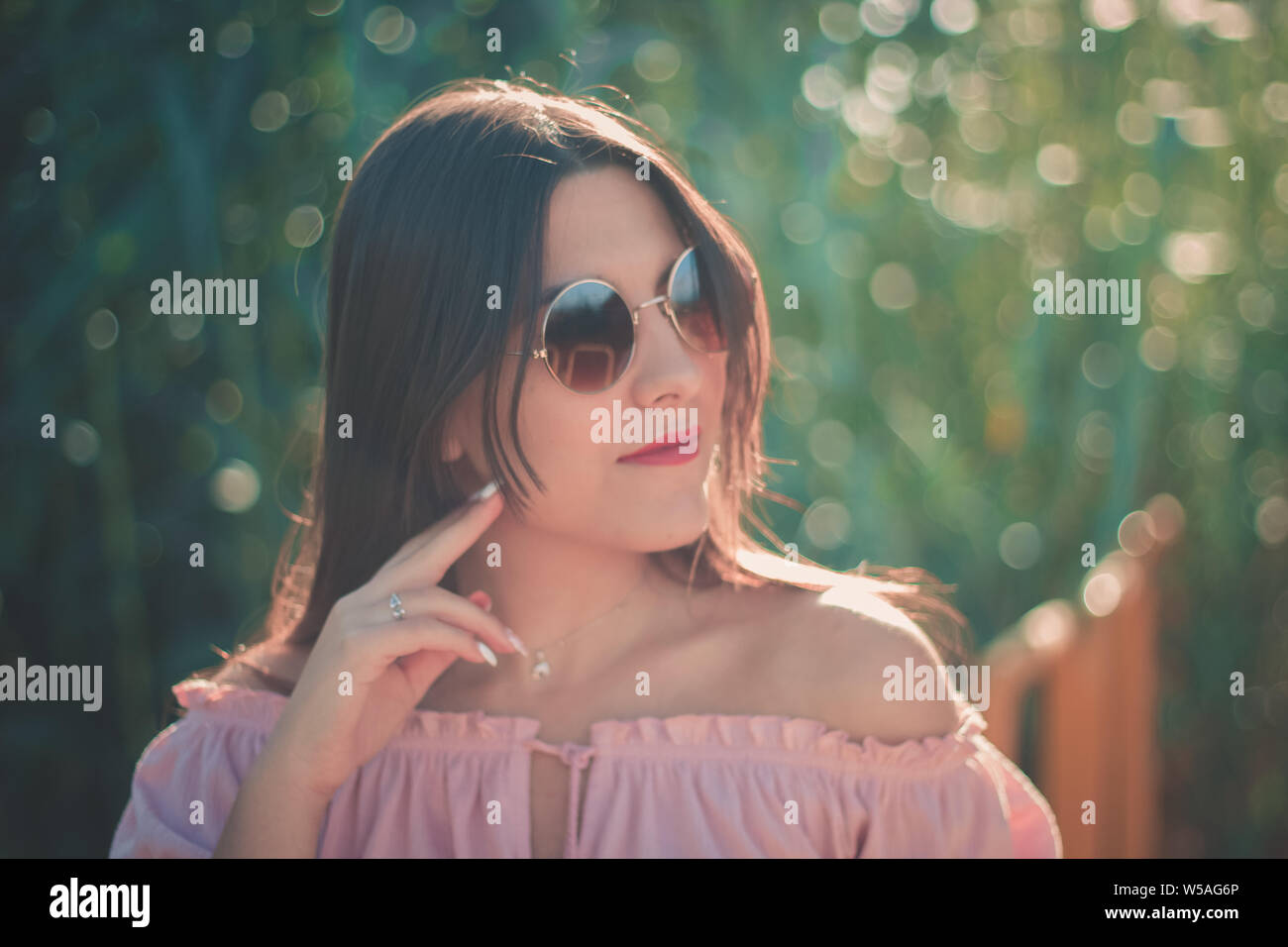 Ritratto di una giovane donna che indossa gli occhiali da sole all'aperto in una giornata di sole Foto Stock