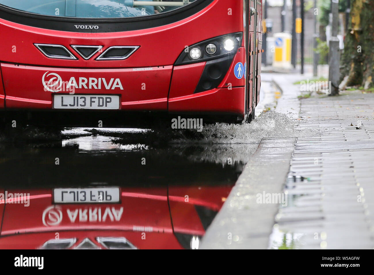 Londra, UK 27 Luglio 2019 - un bus schizzi di acqua quando si aziona attraverso un alluvione sulla Green Lanes nel nord di Londra, causato dalla pesante acquazzone durante la notte. Credito: Dinendra Haria/Alamy Live News Foto Stock