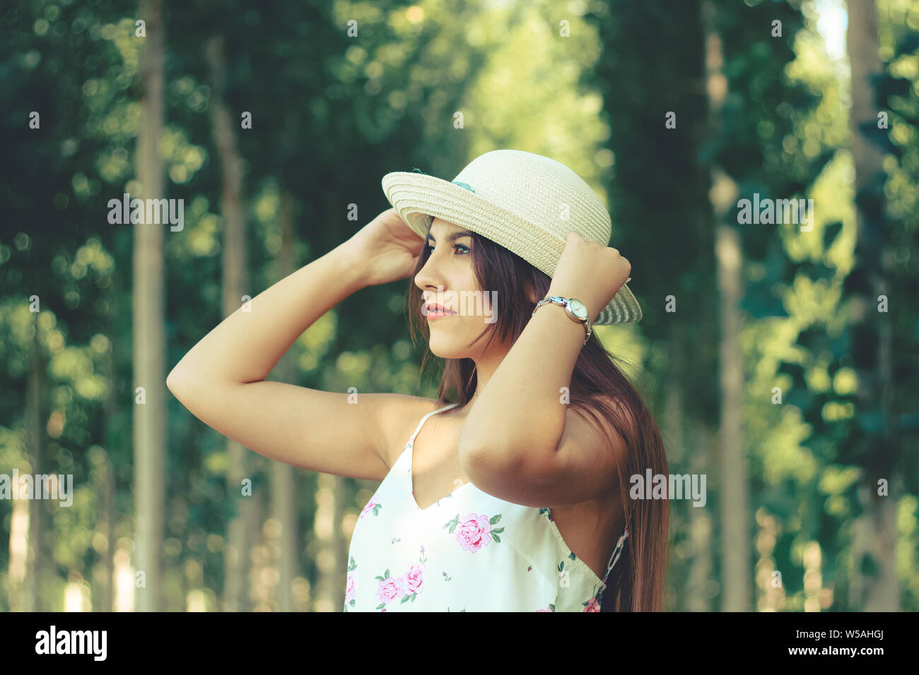 Ritratto di un giovane brunette bella ragazza outdoor indossando sun white hat e fiorito di abiti estivi Foto Stock