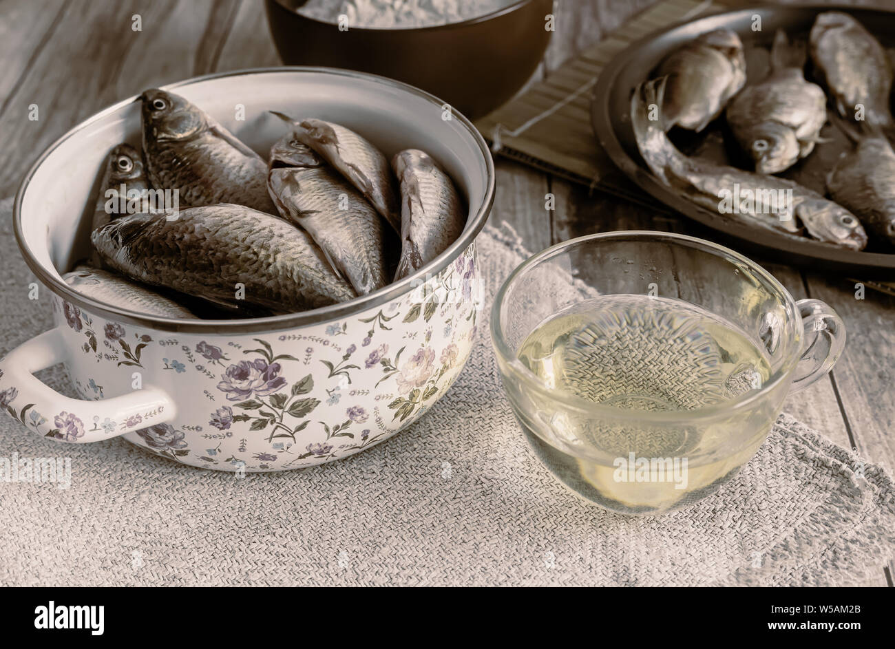 Sul tavolo è cucinato per la frittura di pesce di fiume, vicino a olio e farina di pesce, già fritti in padella. Foto Stock