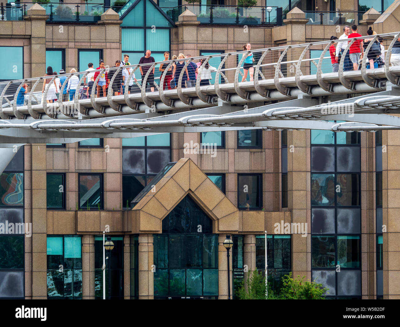 Londra turisti pendolari e attraversare il Ponte del Millennio attraverso il fiume Tamigi. Il ponte in acciaio aperta nel 2000 e costo di £ 18 milioni di euro per costruire. Foto Stock