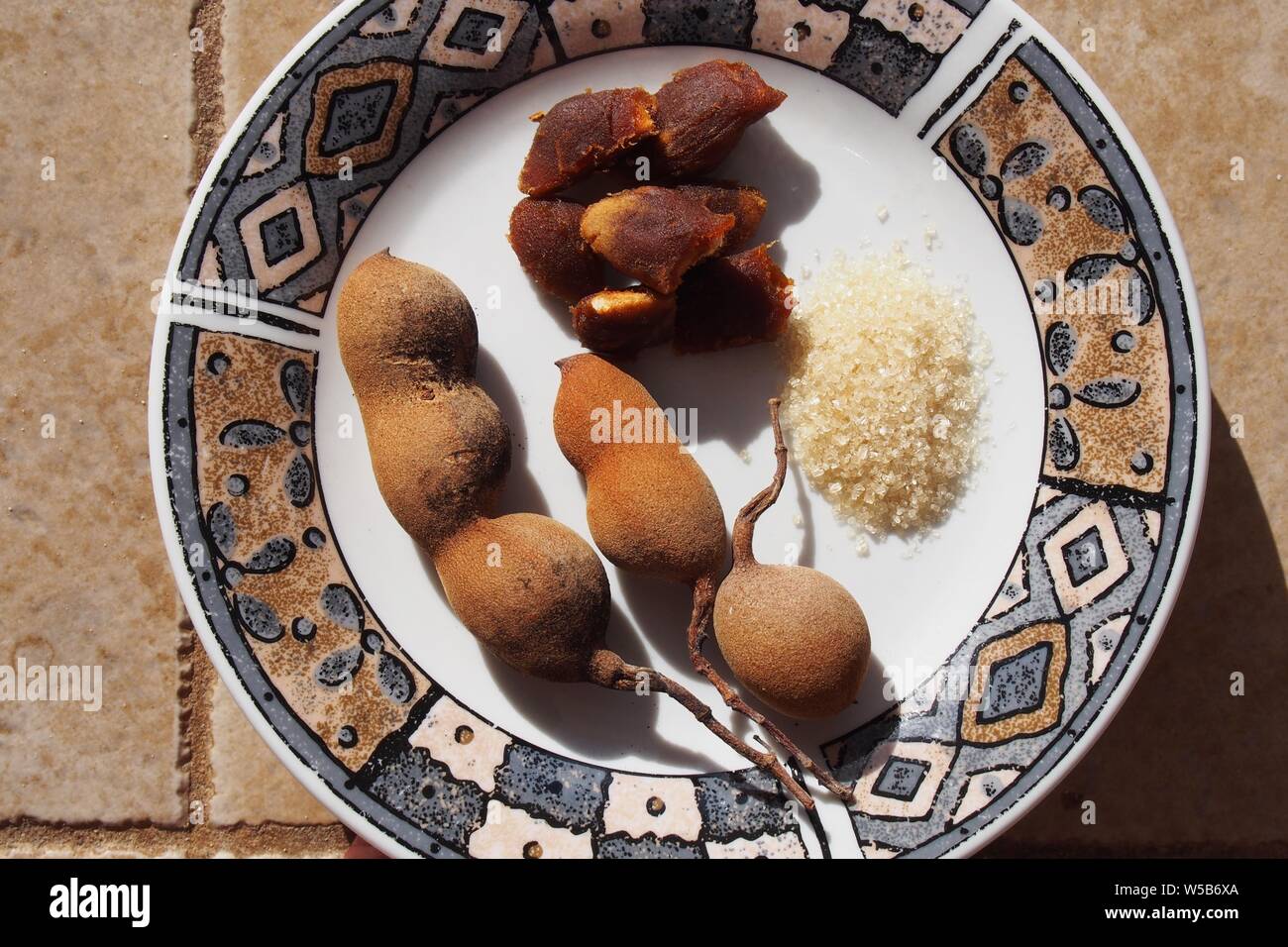 Fresca (Tamarindo Tamarindus indica) cialde e polposo frutto su una piastra con lo zucchero di canna, mangiato come uno snack, Anguilla BWI. Foto Stock