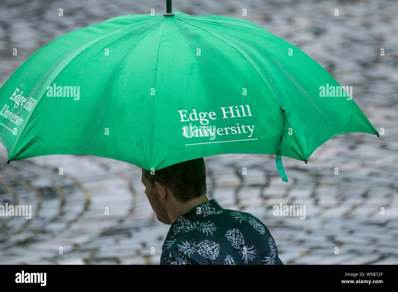 Grande ombrello verde. Un uomo che promuove la Edge Hill University di Ormskirk, Lancashire, Regno Unito Foto Stock