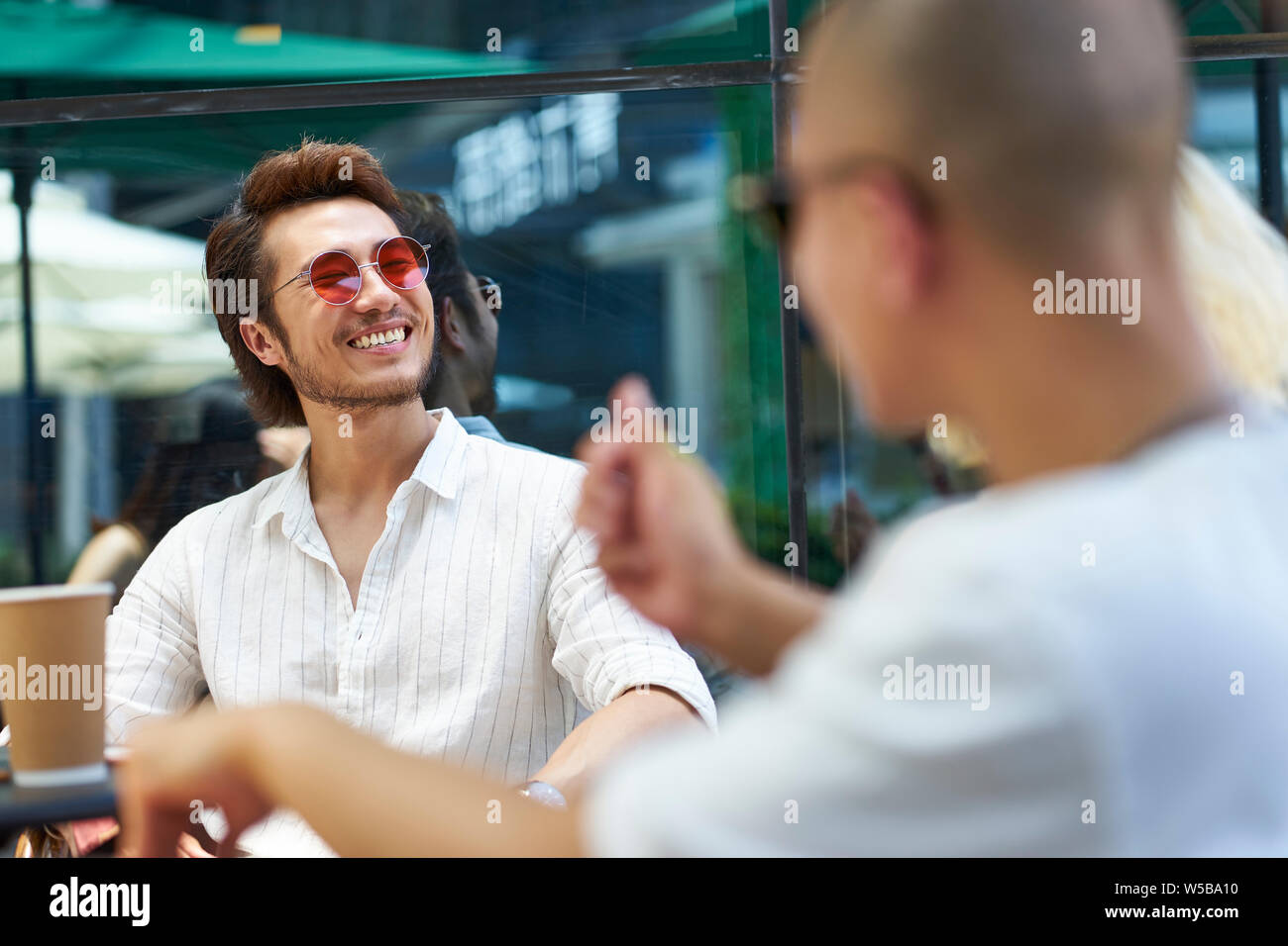 Giovani popoli asiatici l uomo e la donna rilassante chiacchierando in outdoor coffee shop Foto Stock