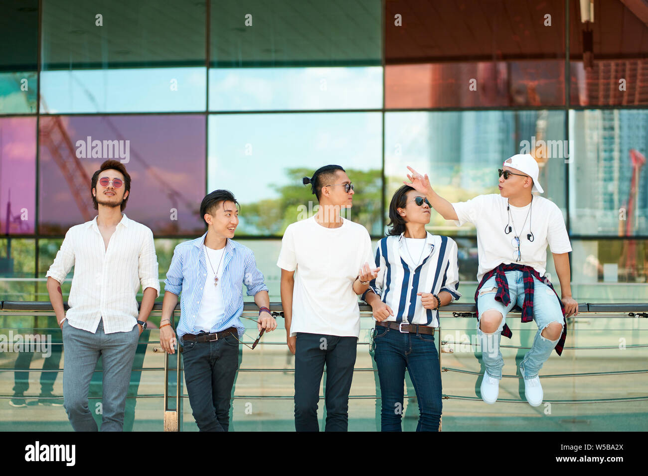 Un gruppo di cinque giovani adulti asiatici appendere fuori insieme sulla strada Foto Stock
