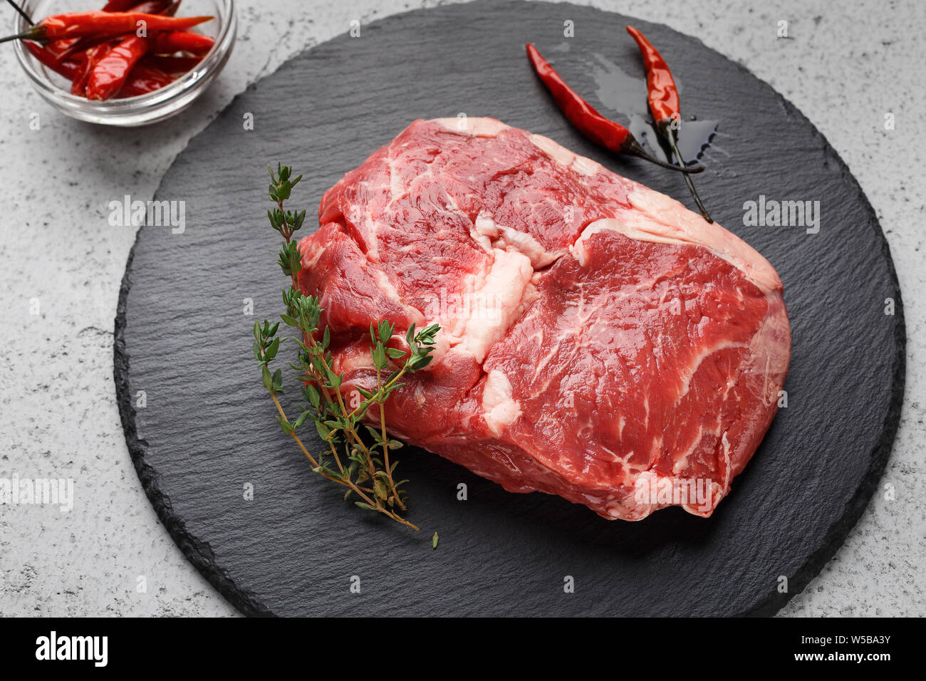 Pezzo di carne di manzo crudo chop sulla lavagna nera, primo piano Foto Stock