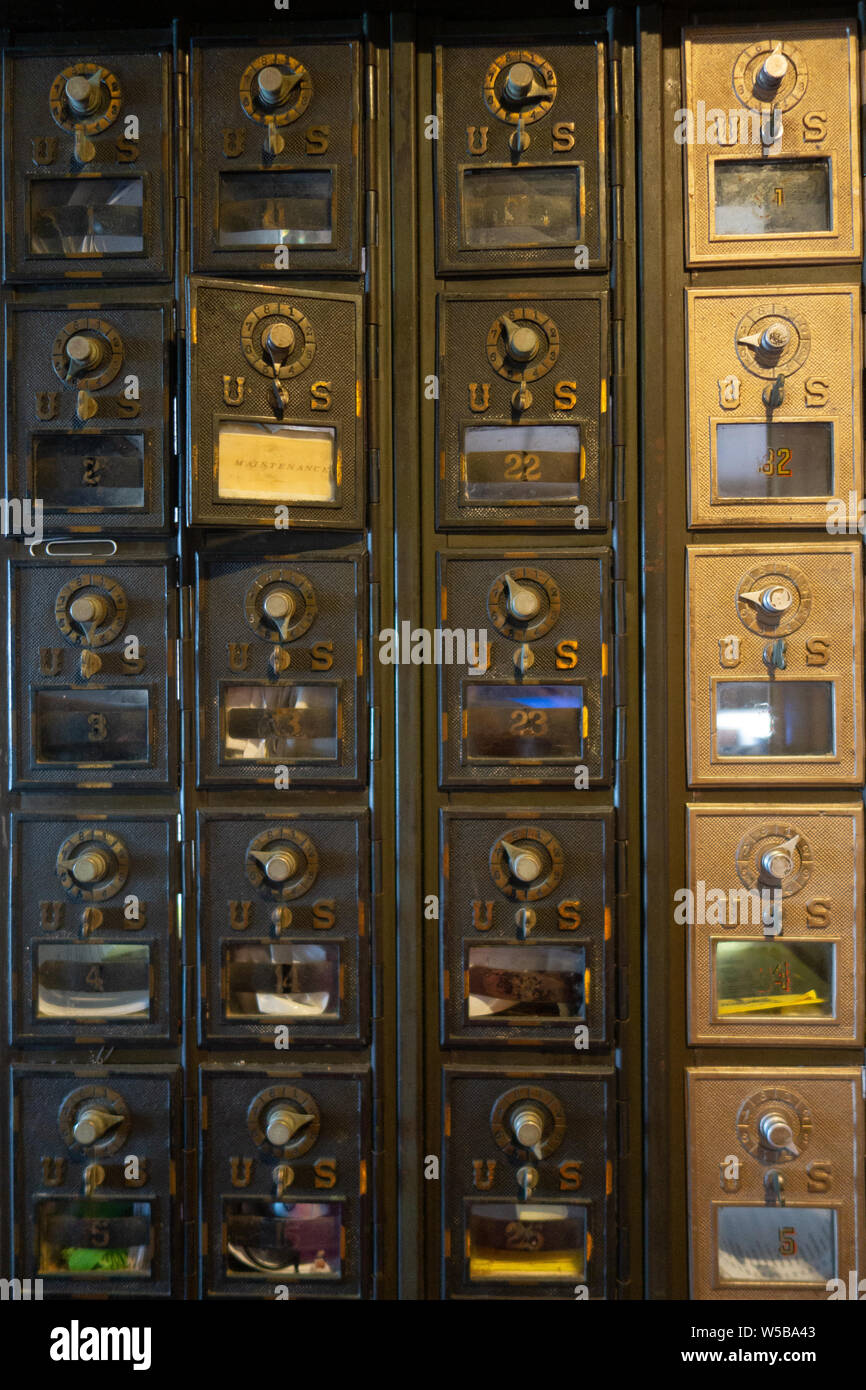 Vista ravvicinata delle cassette postali statunitensi vintage con sportelli in ottone numerati e serrature a combinazione all'interno di un ufficio postale Foto Stock