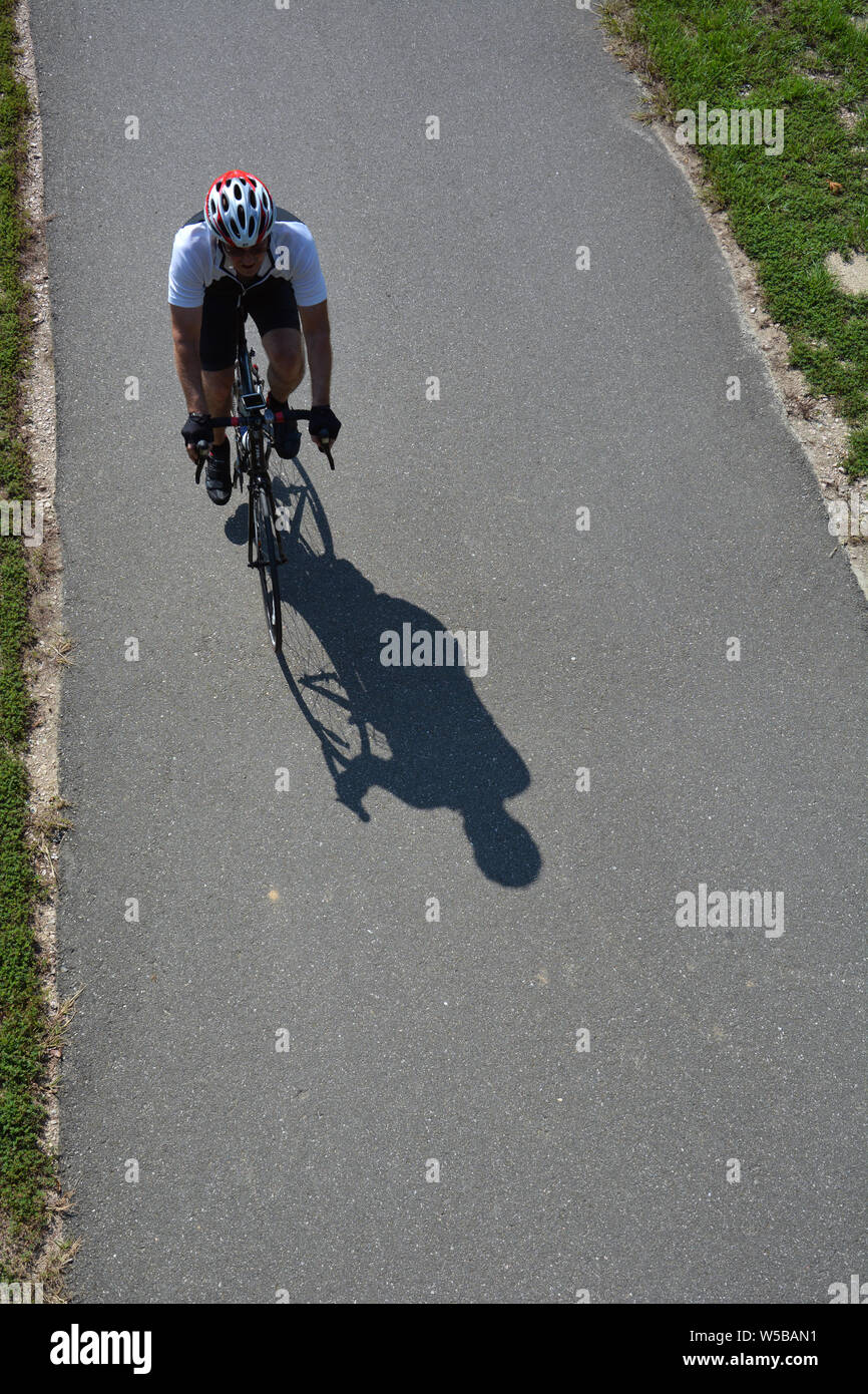 Guardando verso il basso in corrispondenza di un ciclista a cavallo lungo il fiume Neuse Trail durante una calda giornata estiva in Raleigh, North Carolina. Foto Stock