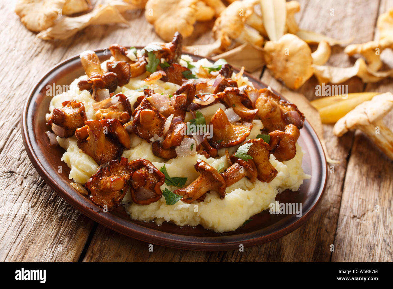 Hot purè di patate servita con finferli fritto close-up su una piastra sul tavolo orizzontale. Foto Stock