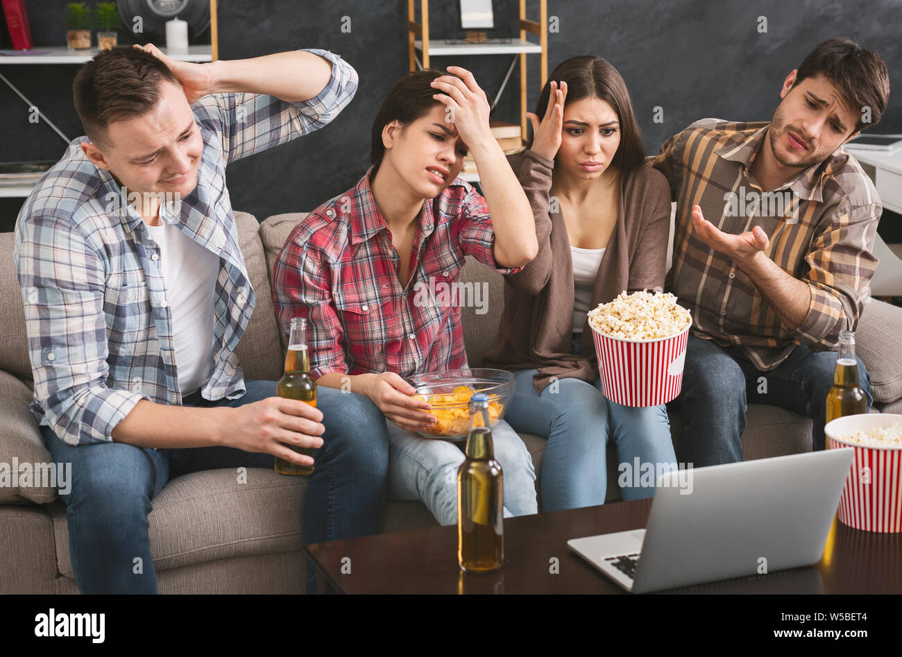 Delusi diversi amici guardare la partita di calcio sul portatile a casa Foto Stock