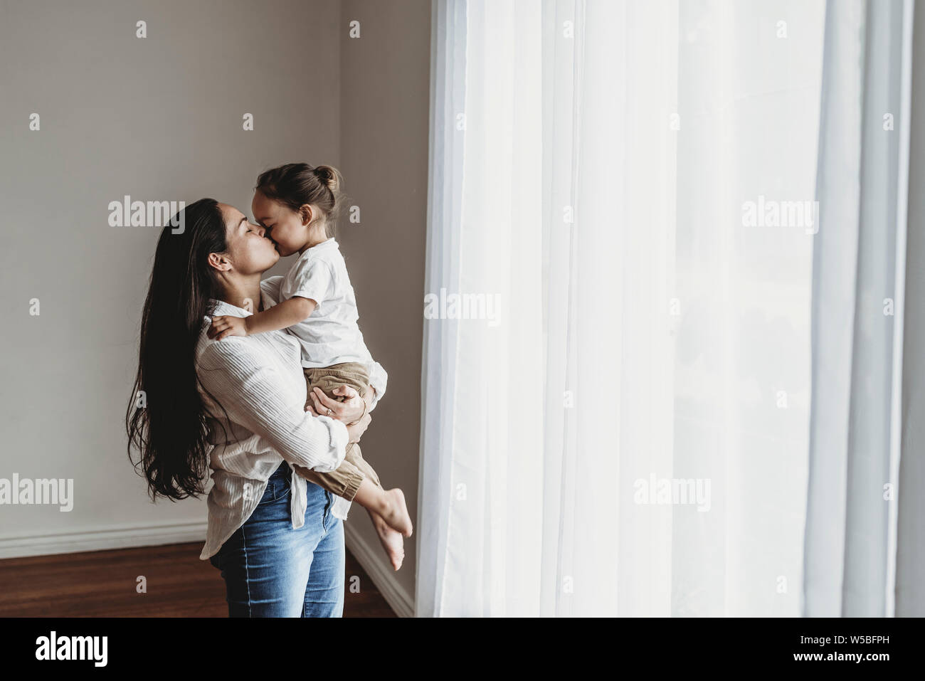 Giovane madre con capelli lunghi tenendo toddler boy e baciare in studio Foto Stock