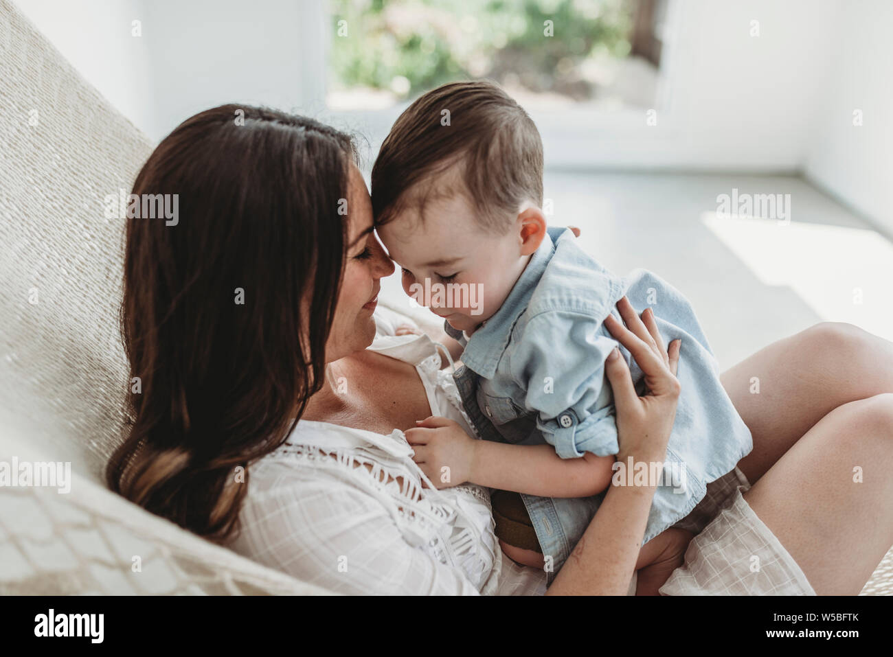 Madre e figlio giovane cuddling in amaca di luce naturale e in studio Foto Stock