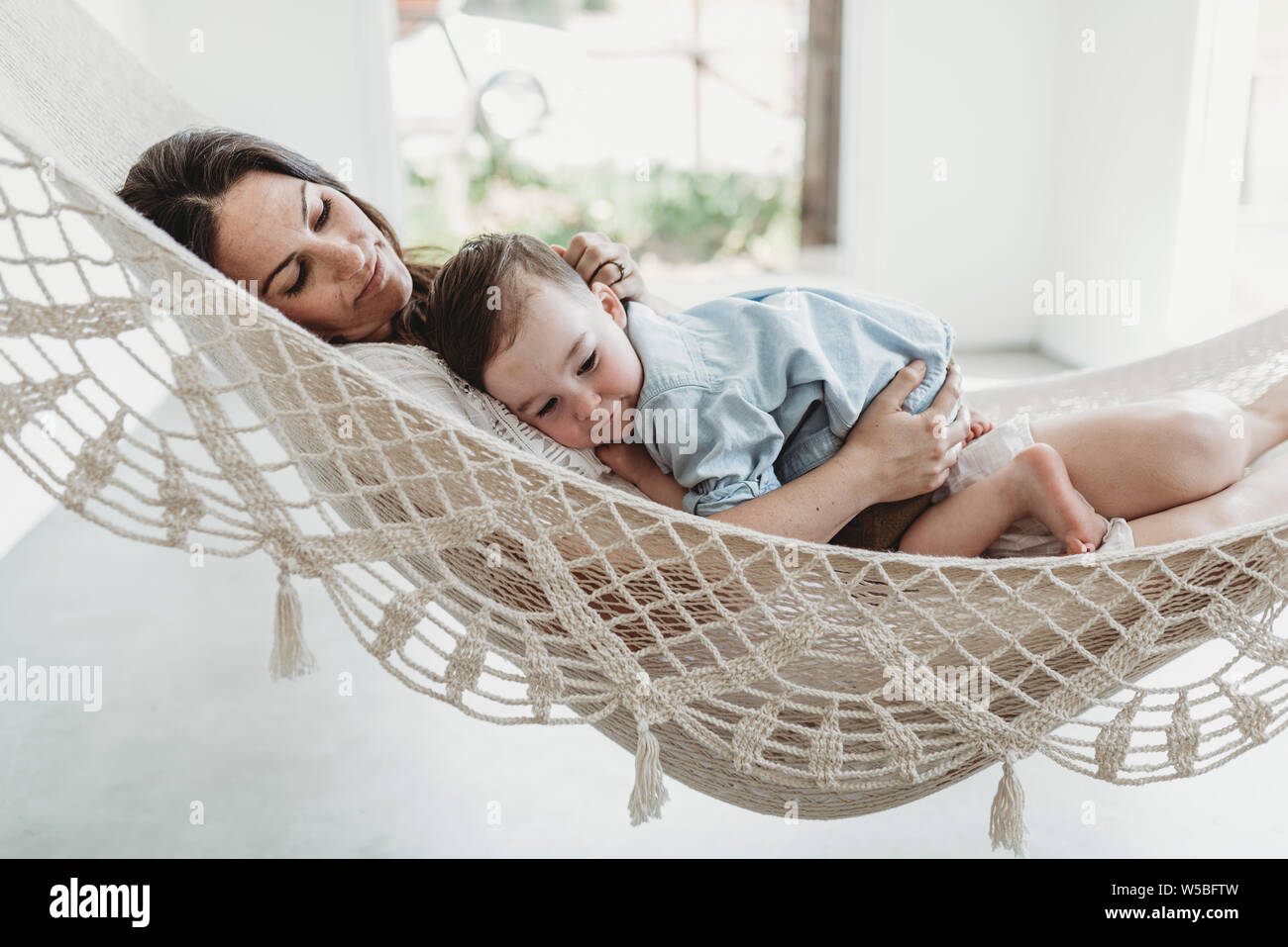 Giovane donna incinta cuddling con il figlio in amaca in studio Foto Stock