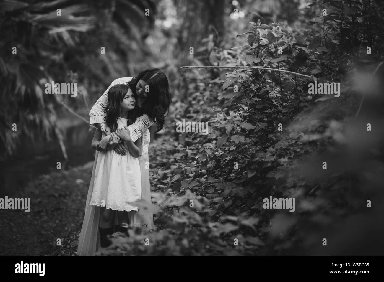 Madre e figlia abbracciando e guardando ogni altra nei boschi Foto Stock
