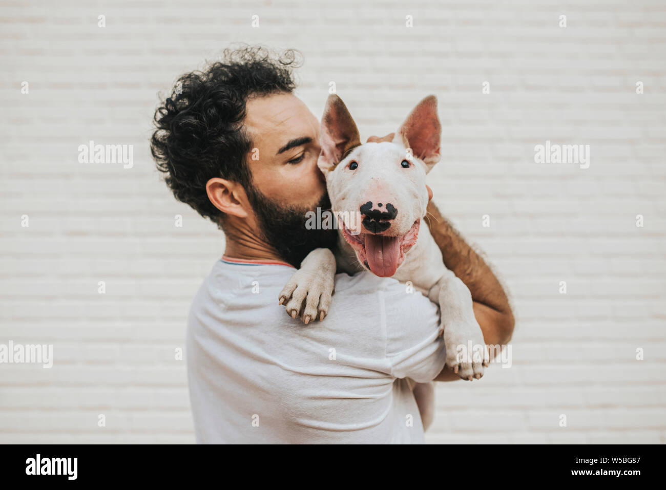 Uomo Barbuto baciando un white bull terrier cane Foto Stock