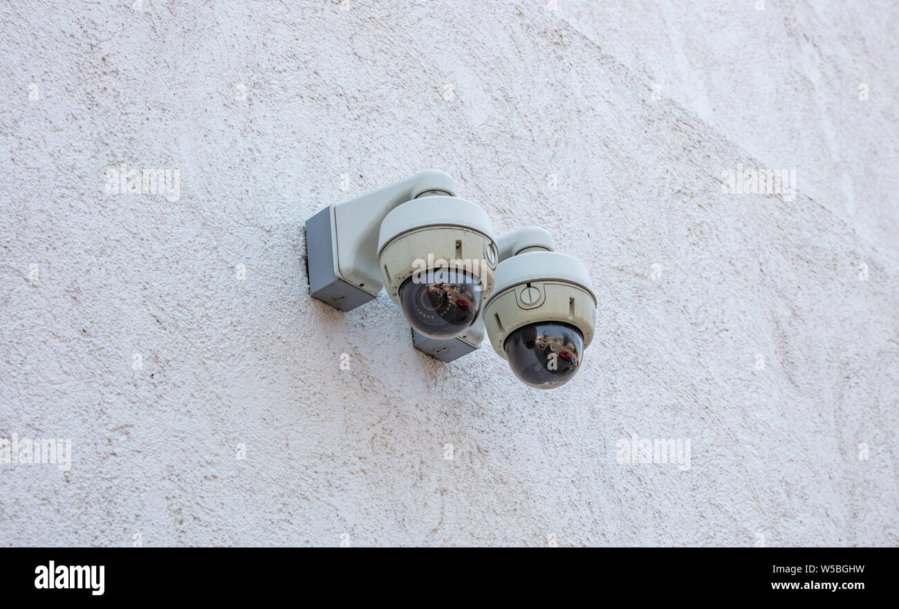 Protezione di telecamere di monitoraggio sistema TVCC, all'aperto su un colore bianco edificio parete di facciata. Sicurezza, privacy concetto. Foto Stock