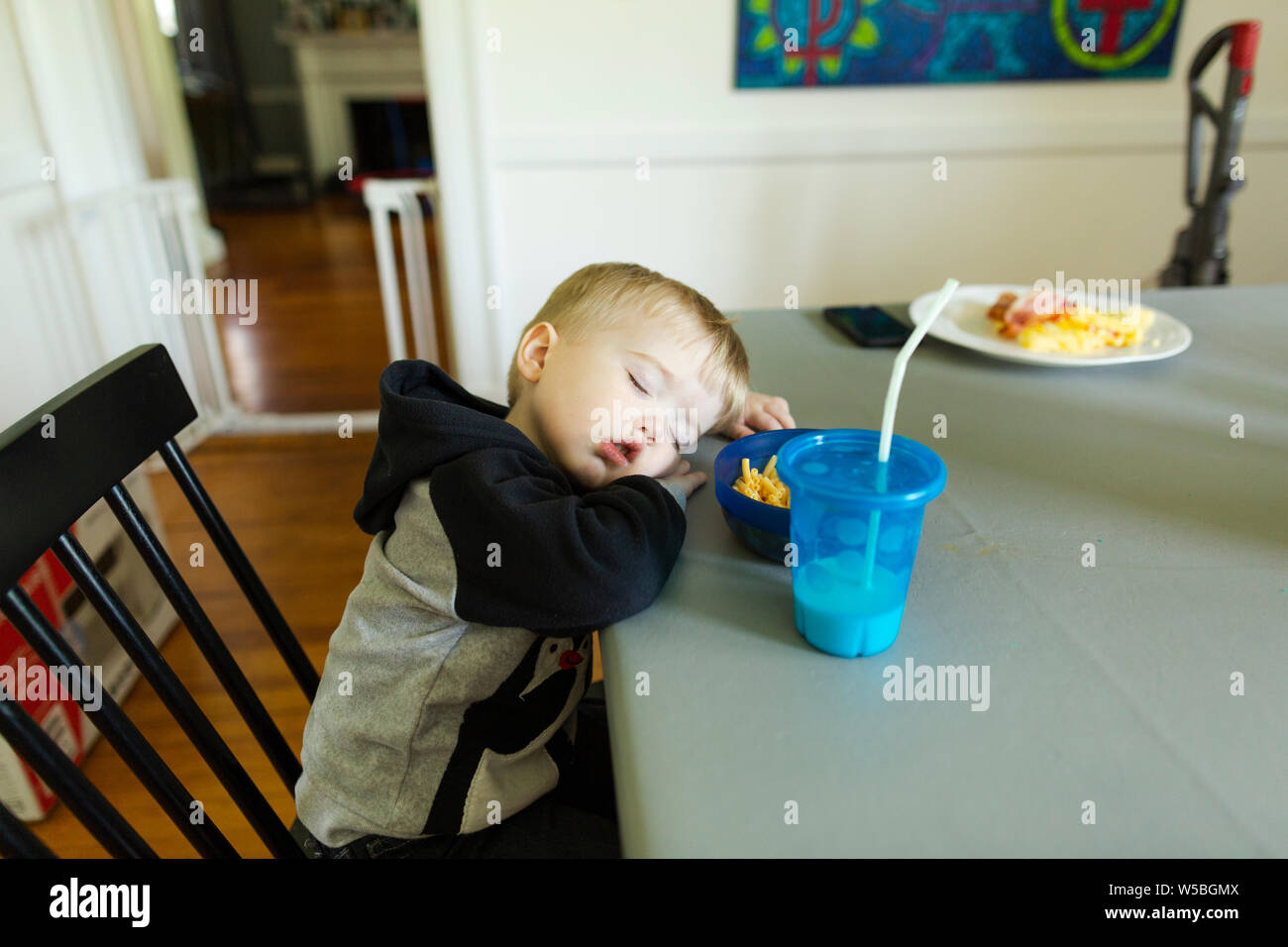 Il Toddler boy addormentato in cattedra al tavolo da pranzo durante i pasti Foto Stock
