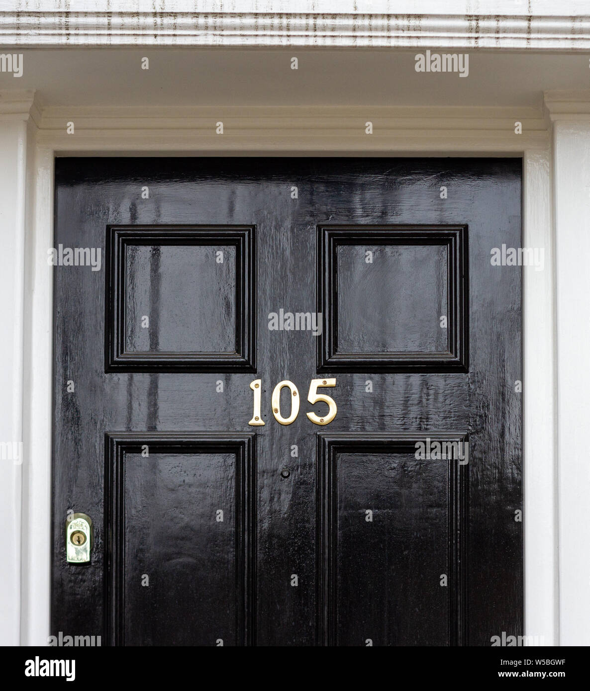 Numero civico 105 su di un legno nero porta anteriore con visibile del telaio della porta Foto Stock