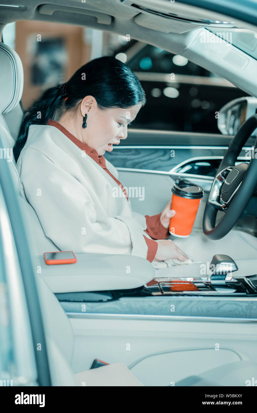 Confuso donna spazzare via il suo caffè versato. Foto Stock